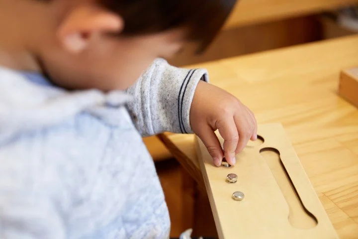 A toddler is working on a wooden montessori job at playgroup