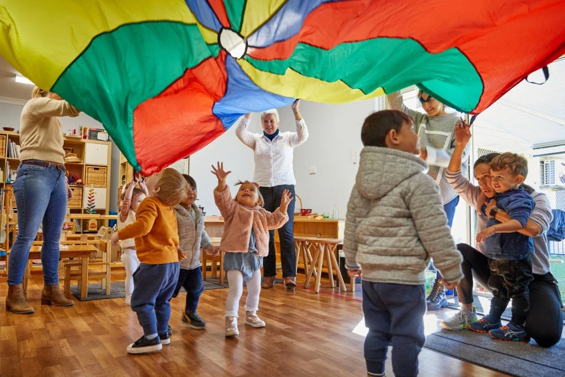 Children playing indoors at playgroup, supervised by adults.