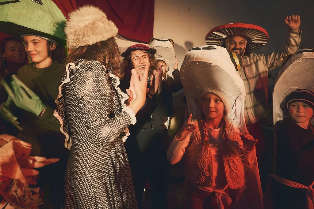 Grupo de personas, incluyendo niños y adultos, en una celebración con disfraces de sombreros grandes y coloridos, en un ambiente festivo y alegre.