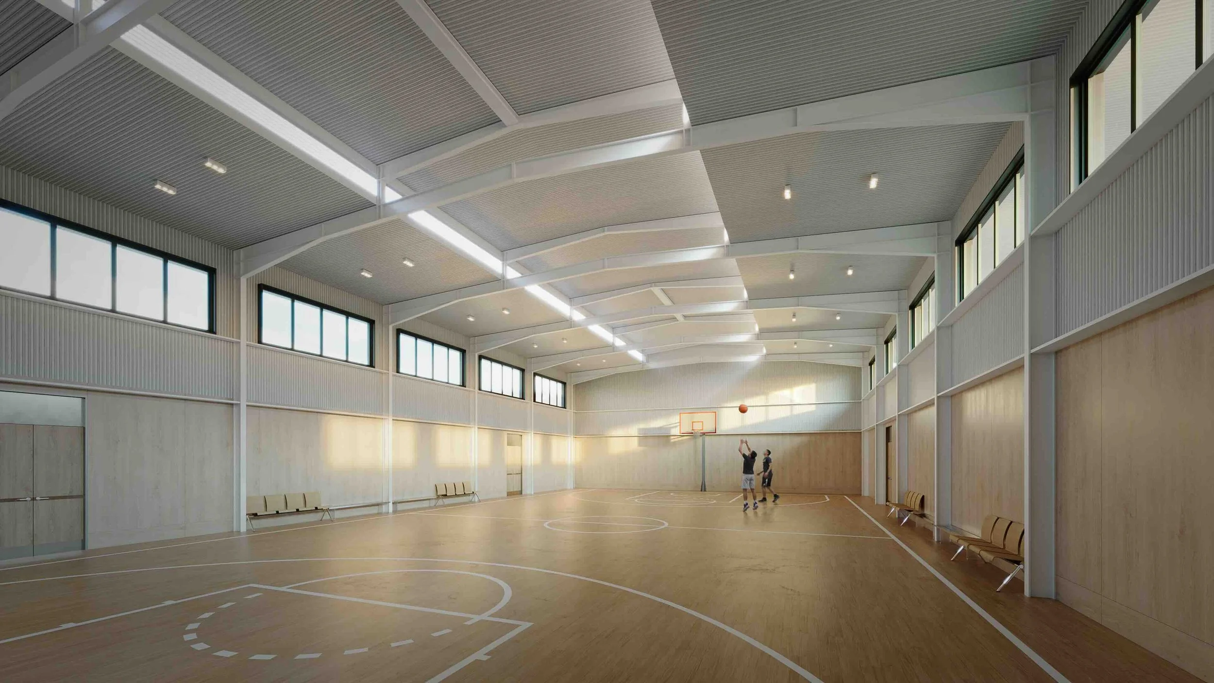 An artist perspective of one of Susana Heights amenities: the basketball court. Two people playing basketball in an indoor gymnasium with wooden flooring, high ceiling, large windows, and benches along the walls.