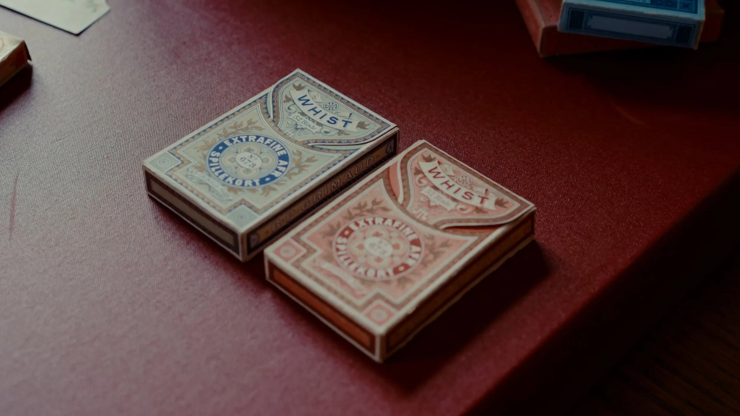 Deux paquets de cigarettes sur une table rouge.