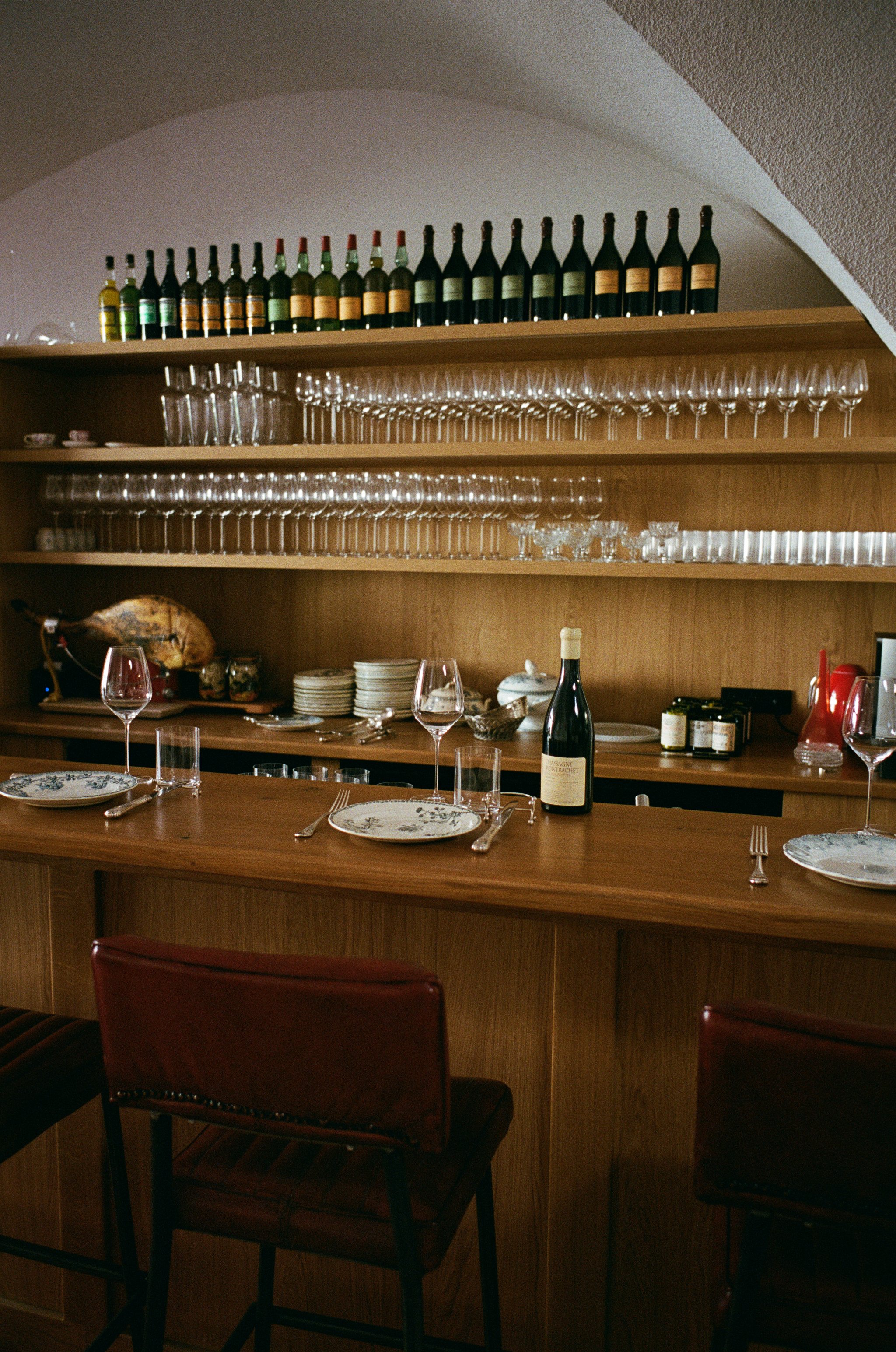 cuisine de bar avec bouteilles de vin, verres, assiettes, et une bouteille de vin sur le comptoir en bois.