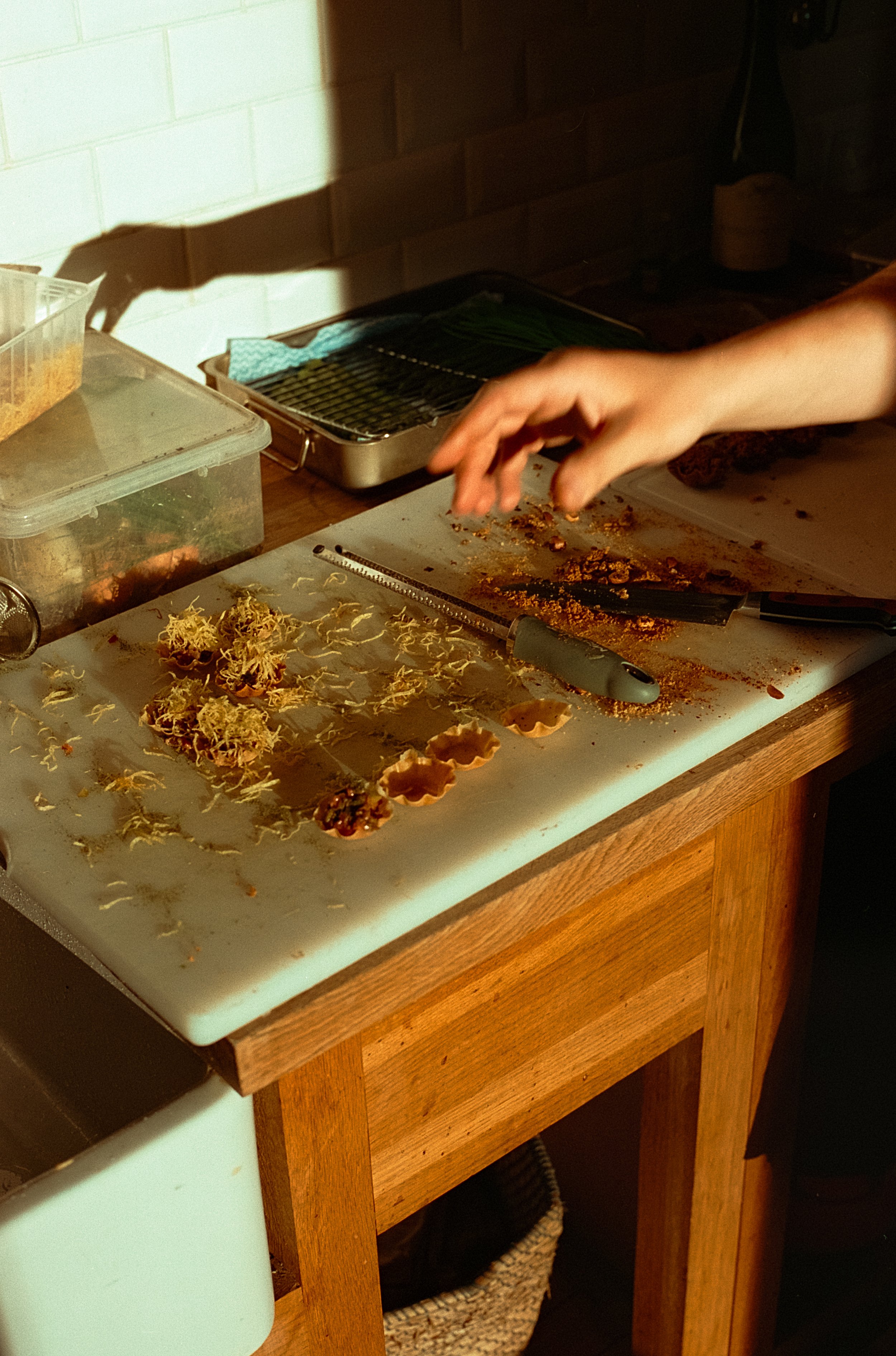 Préparation de nourriture sur une planche en bois, avec des emporte-pièces, des herbes et des couteaux, dans une cuisine