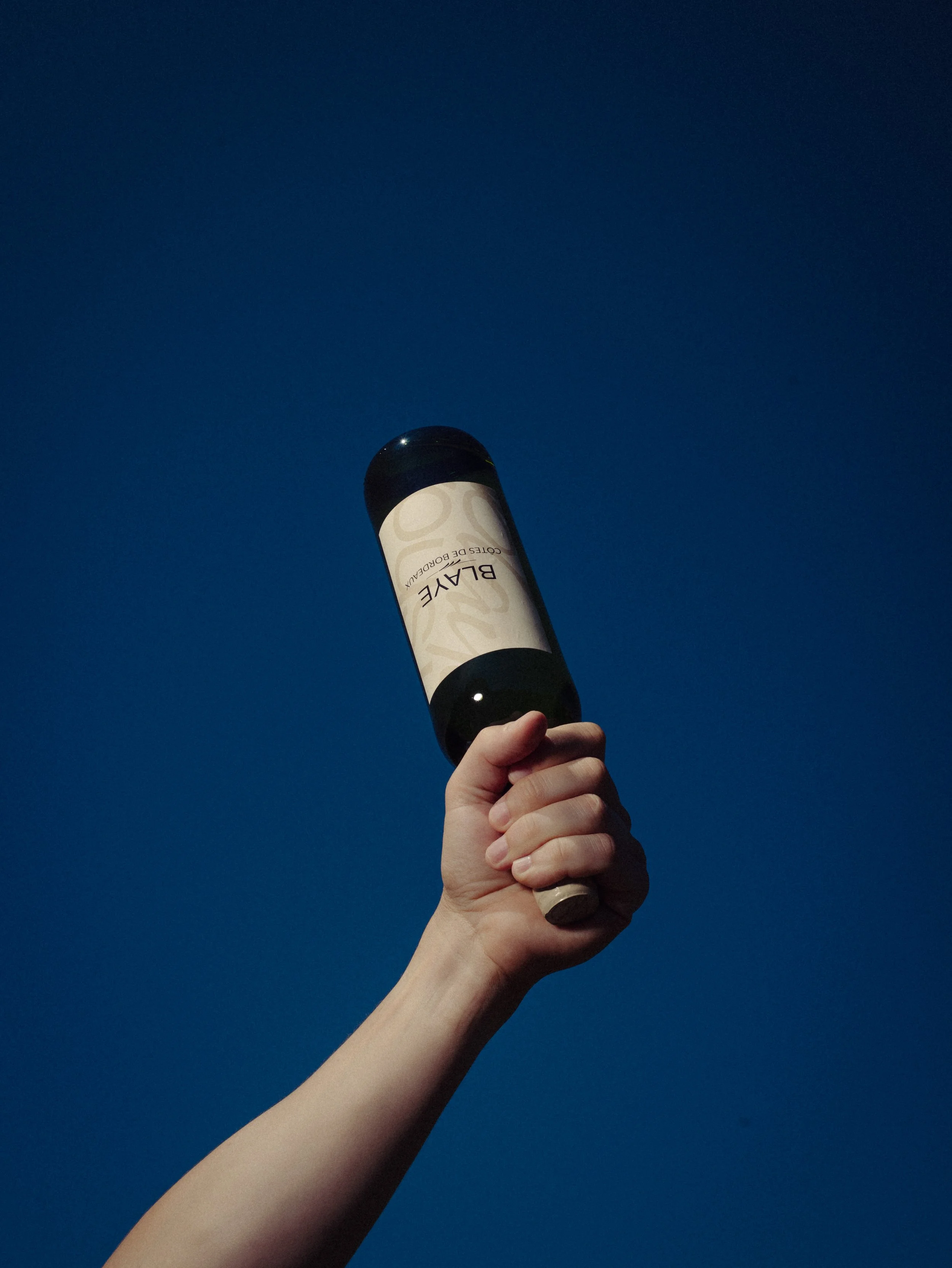 Une main tenant un outil de massage en forme de rouleau contre un ciel bleu clair.