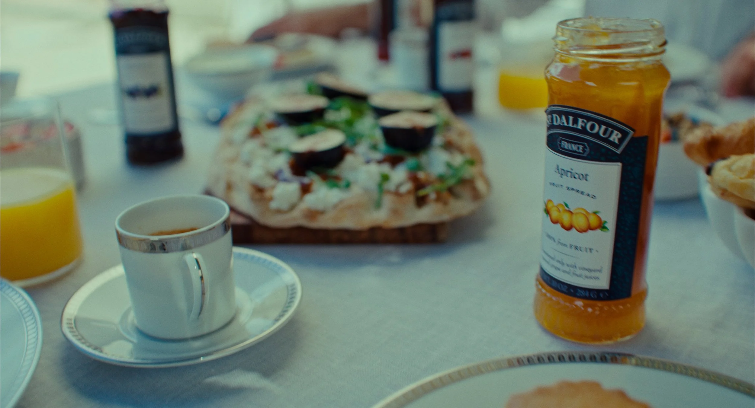 Table avec diverses boissons, un petit gâteau au miel, une pizza et une confiture d'abricot.