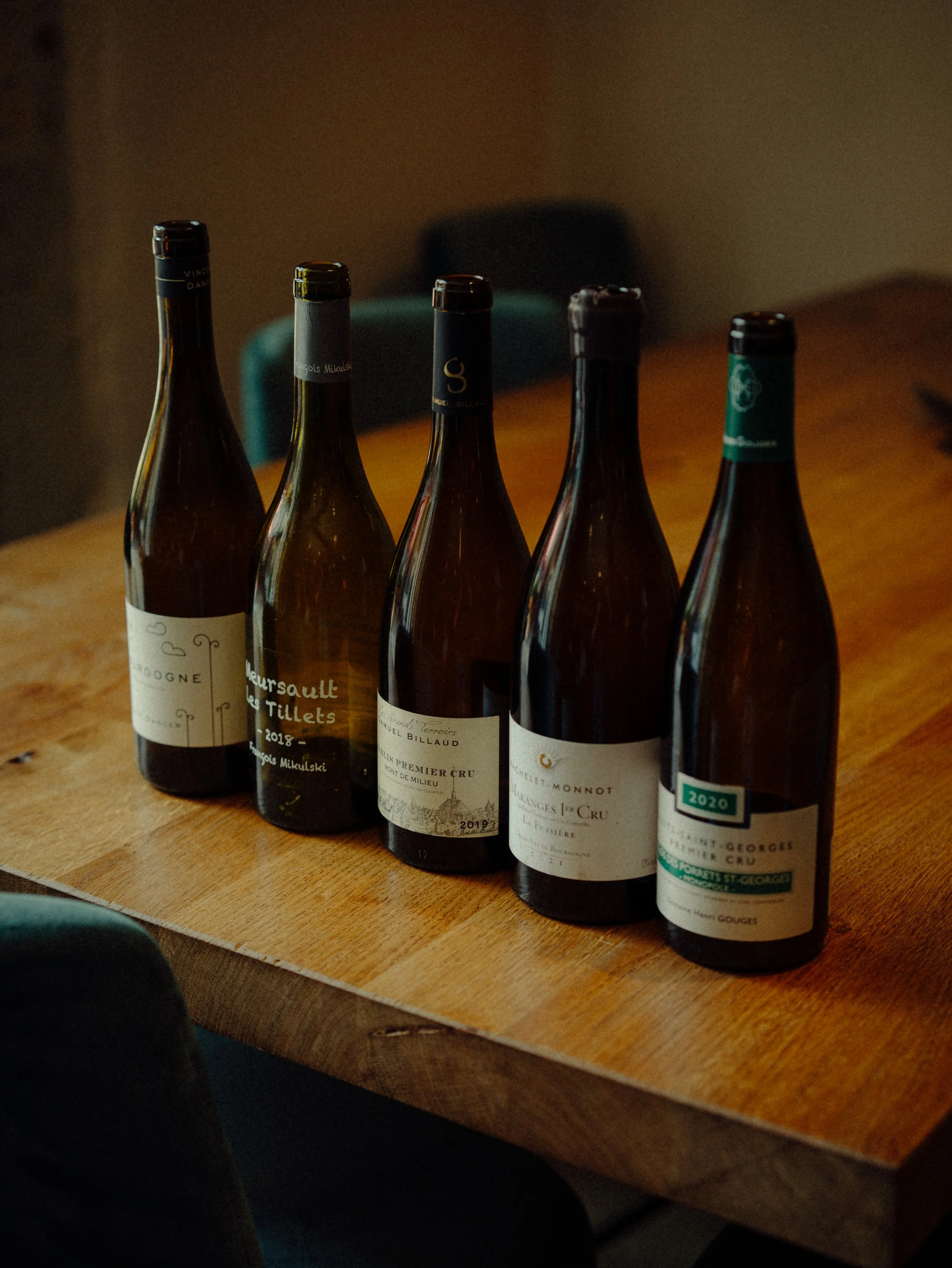 Cinq bouteilles de vin posées sur une table en bois.