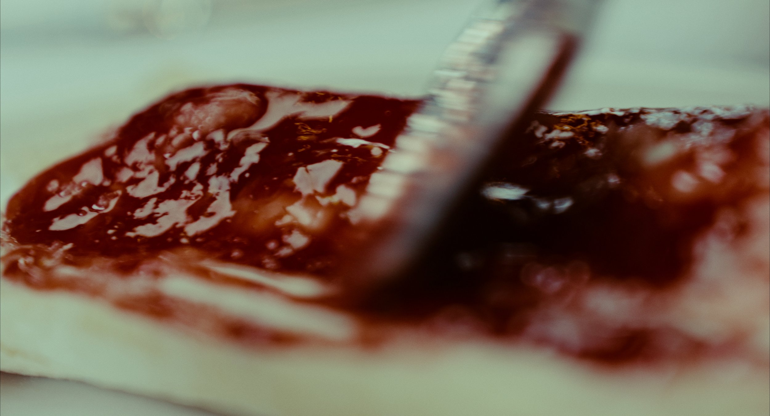 Une tranche de pizza avec du pepperoni, vue en gros plan avec une spatule ou une fourchette en train de couper la pizza.