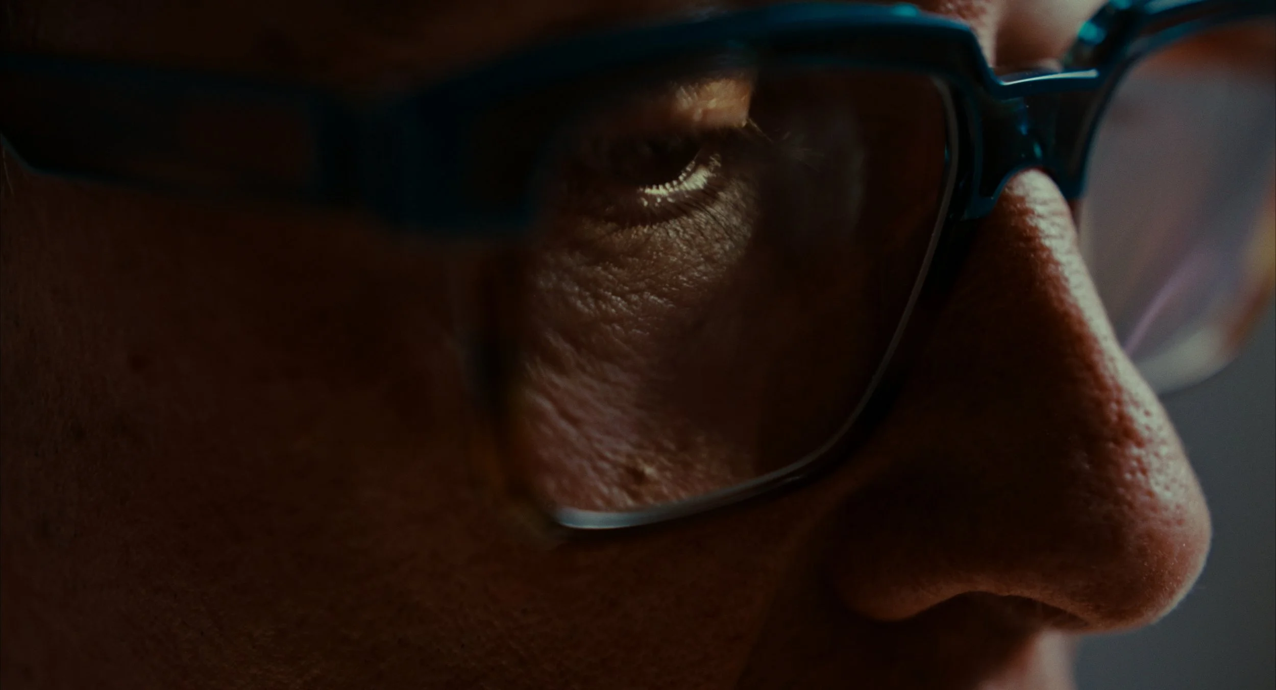 Zoom sur un visage d'une personne portant des lunettes, concentrée ou regardant fixement.