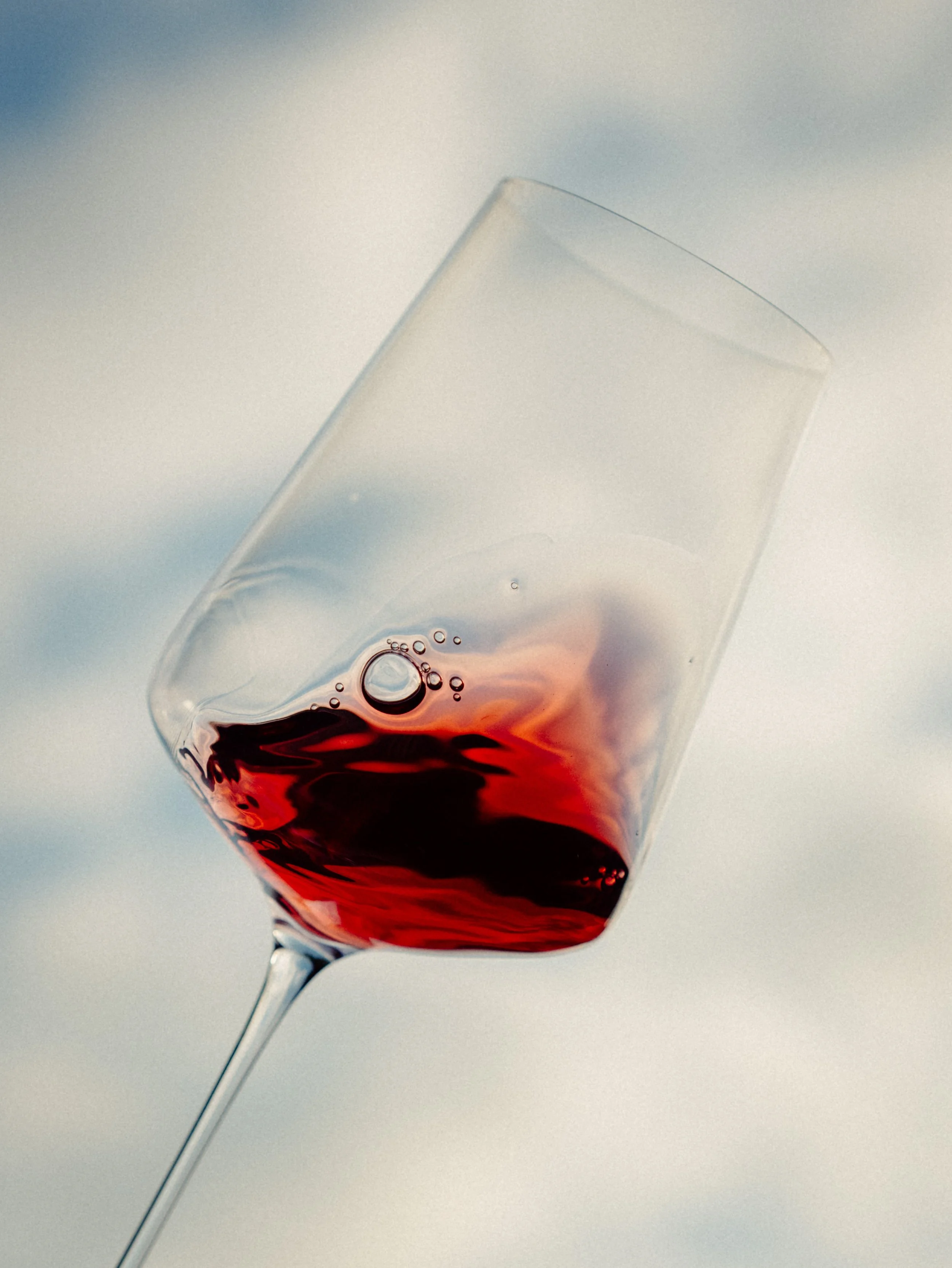 Verre à vin rouge incliné avec une petite quantité de vin à l'intérieur contre un fond flou.