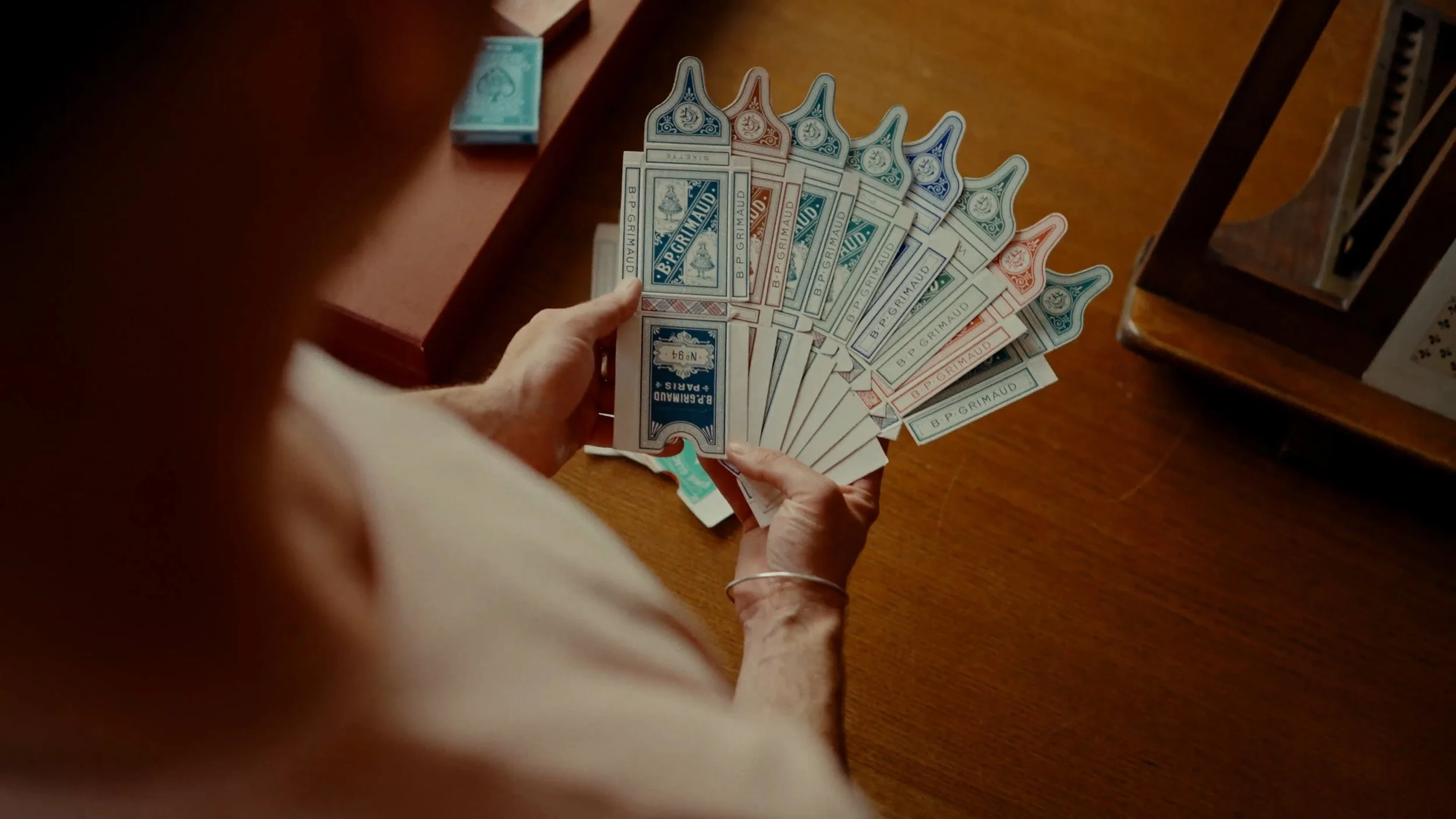 Une personne tenant un éventail de billets de banque de différentes couleurs sur une table en bois.