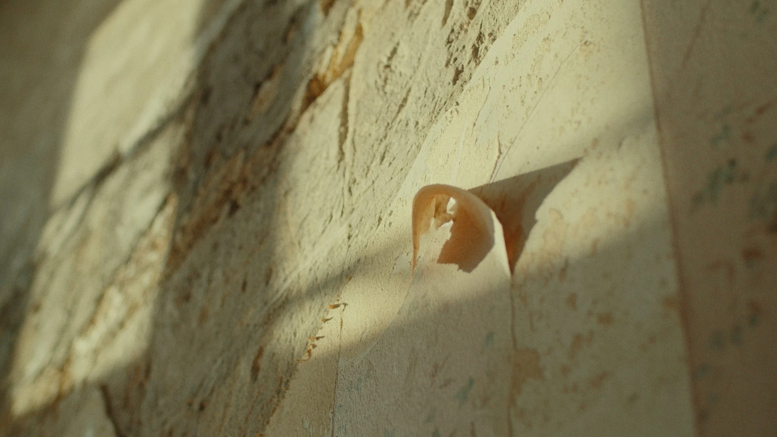 Un trou dans un mur de briques et de plâtre, avec un éclat de peinture ou de plâtre qui dépasse.