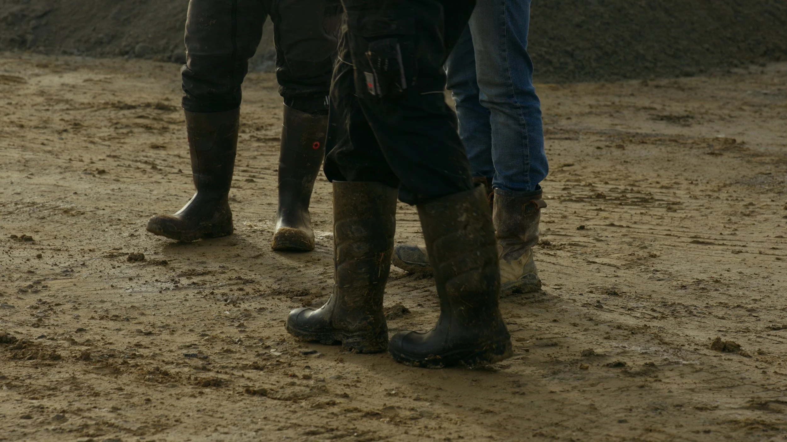 Groupe de personnes portant des bottes en caoutchouc sur un terrain de terre