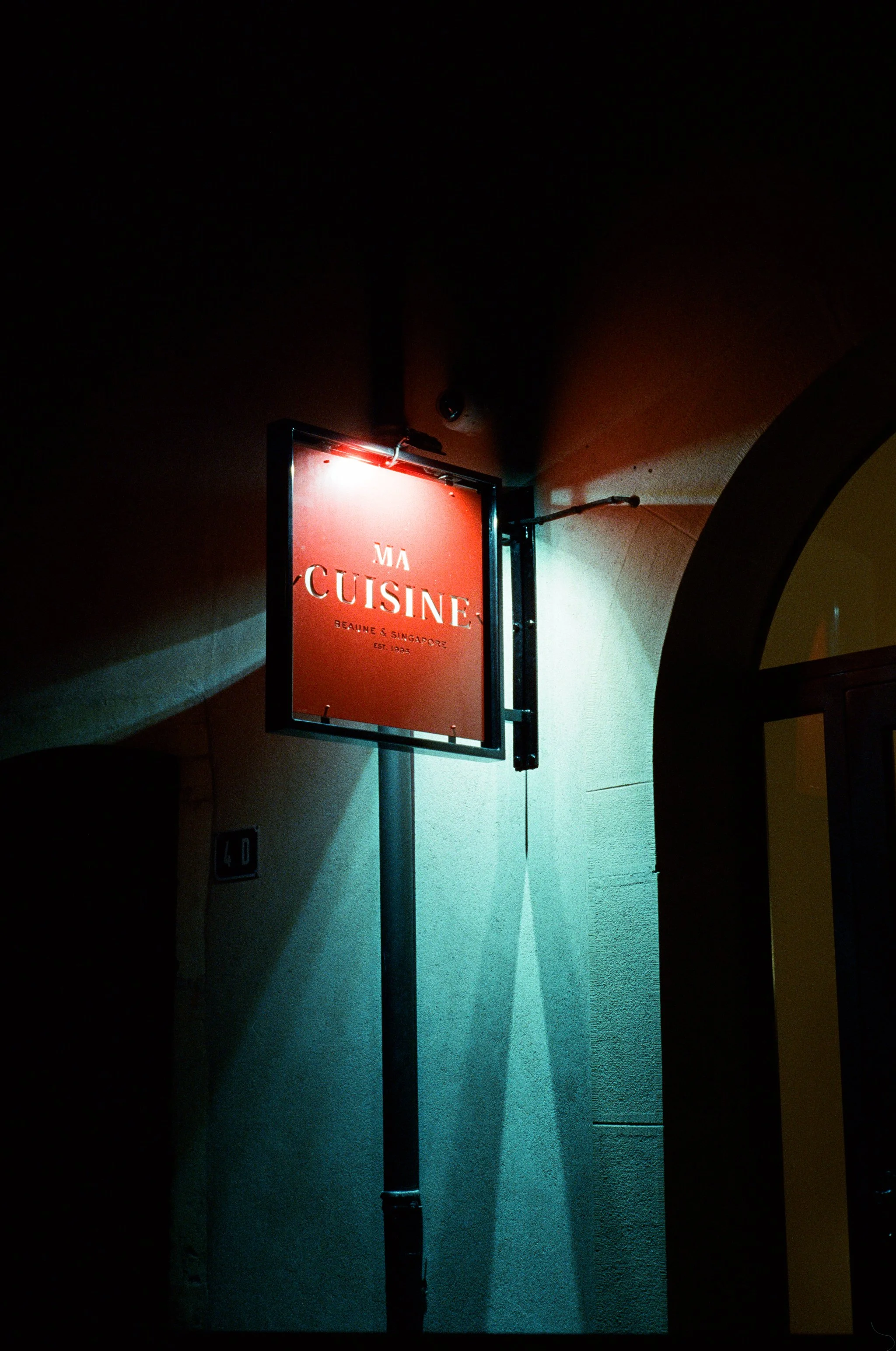 Panneau lumineux rouge avec le texte 'Ma Cuisine' au-dessus d'une porte, dans une ambiance nocturne.