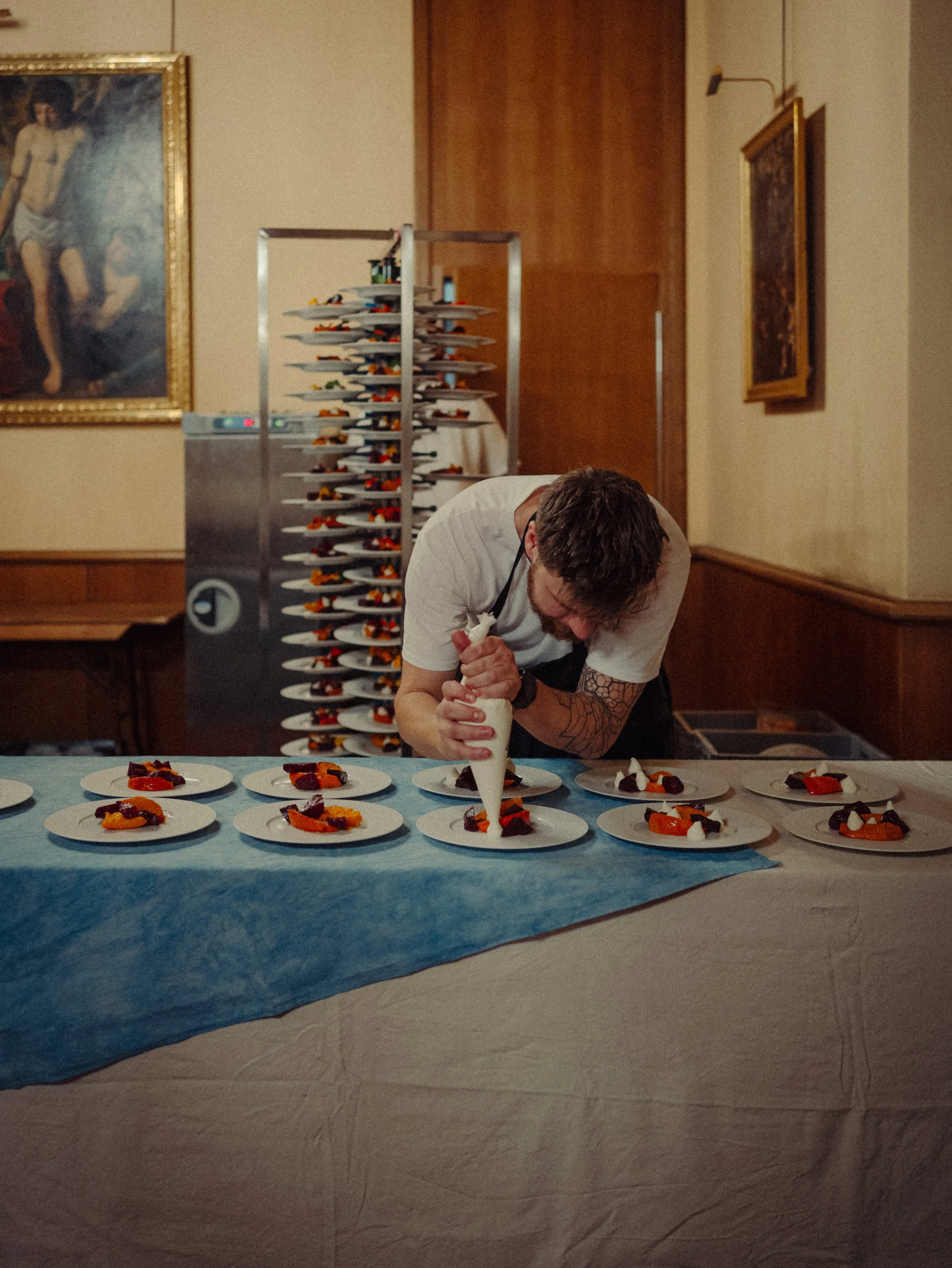 Un chef décore des assiettes de desserts dans une salle de restaurant.
