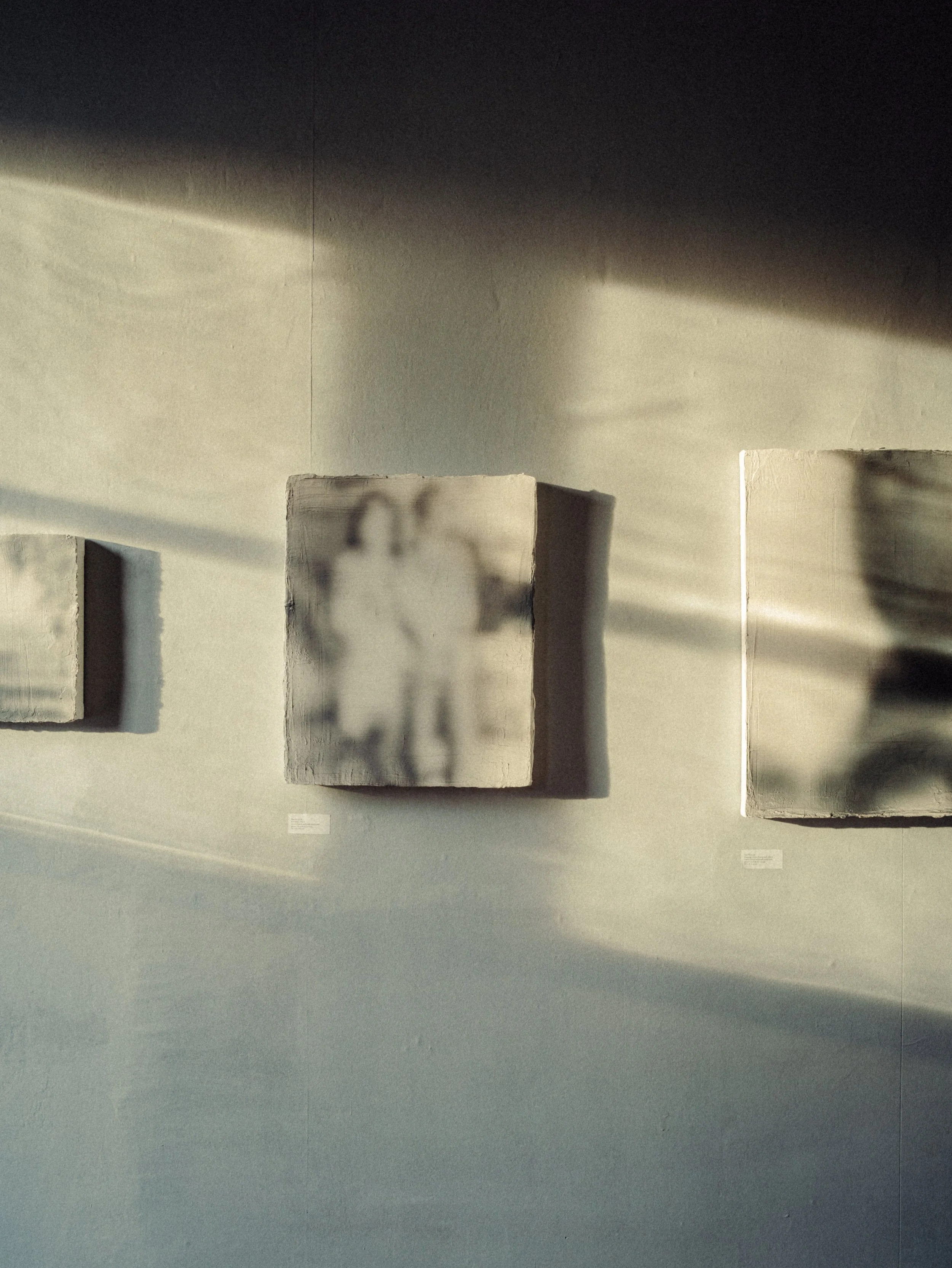 Oeuvres d'art abstraites avec des formes humaines floues sur des blocs de béton, éclairage naturel avec des ombres douces.