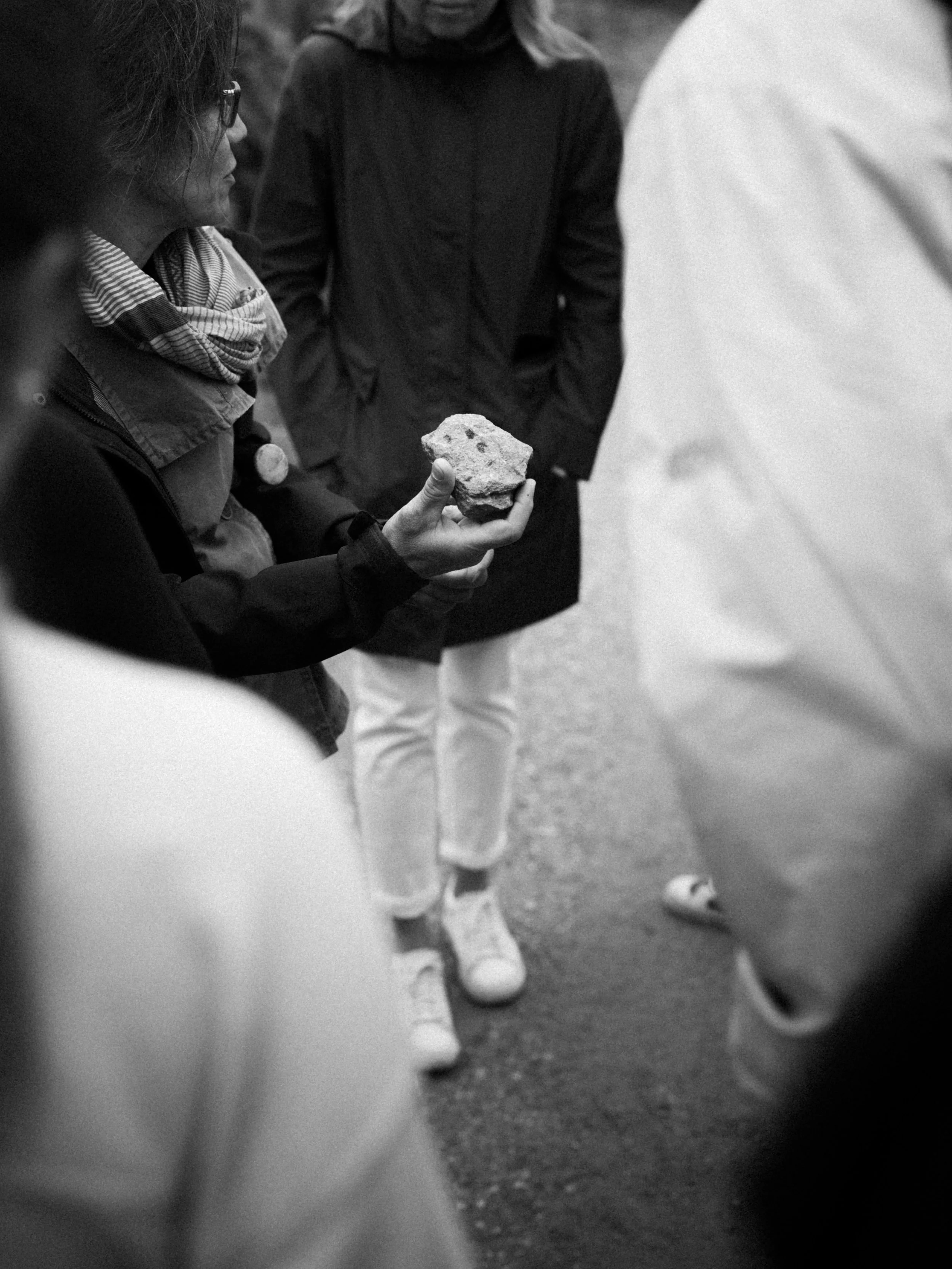 Une personne tient une roche en l'examinant lors d'une sortie en groupe à l'extérieur.