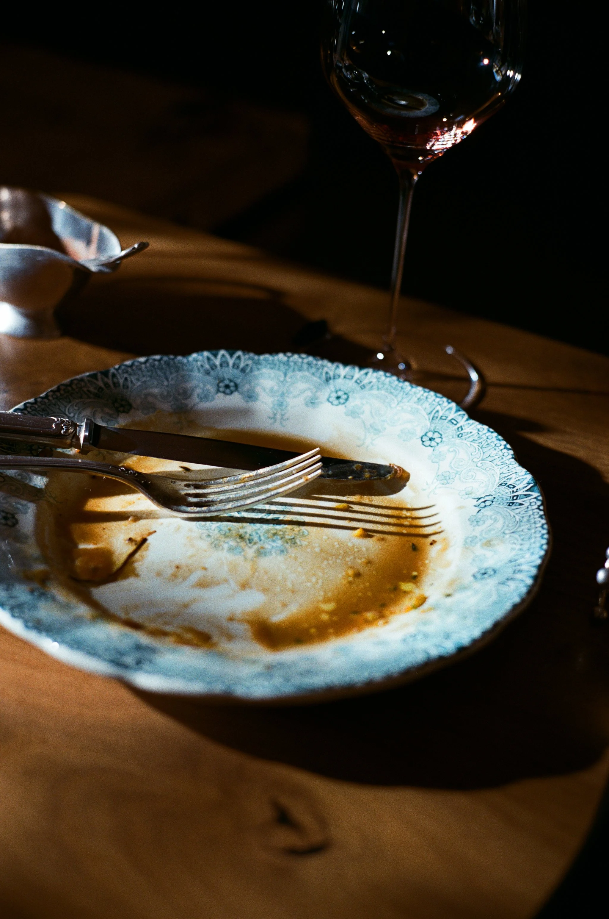 Assiette vide avec des couverts et un verre de vin vide sur une table en bois