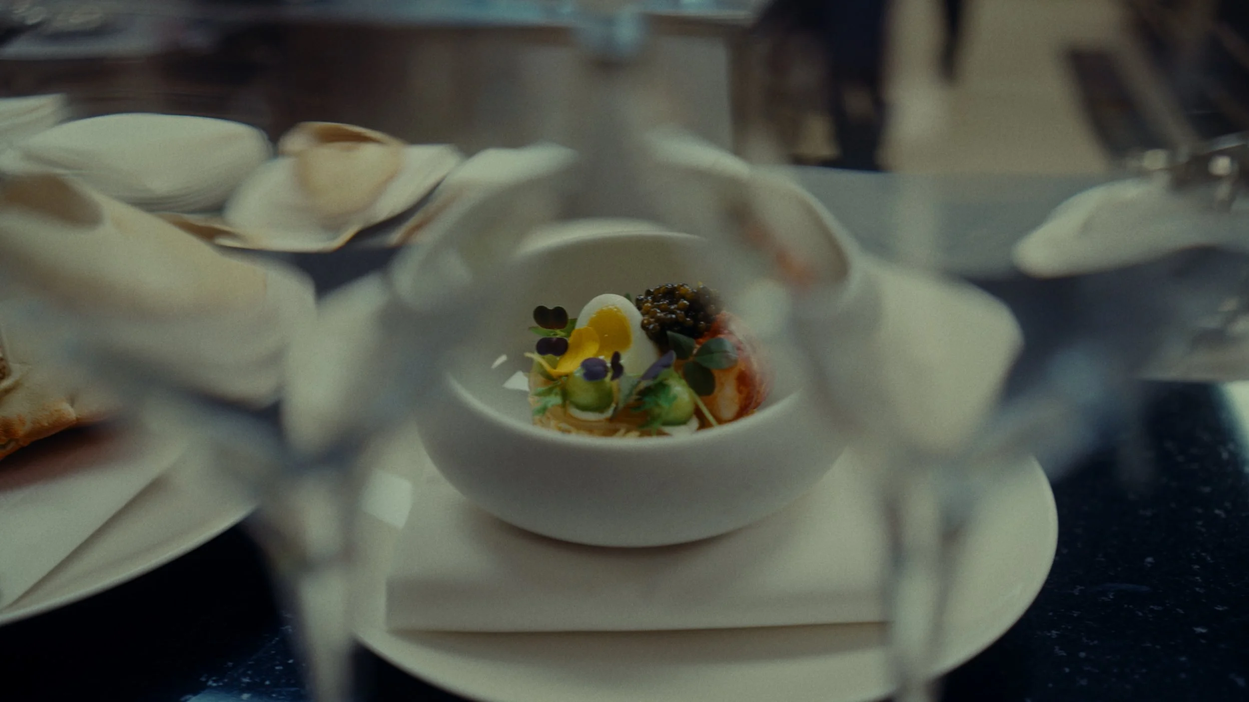 Petit plat gastronomique avec des légumes et des œufs de poisson, vu à travers un verre. 