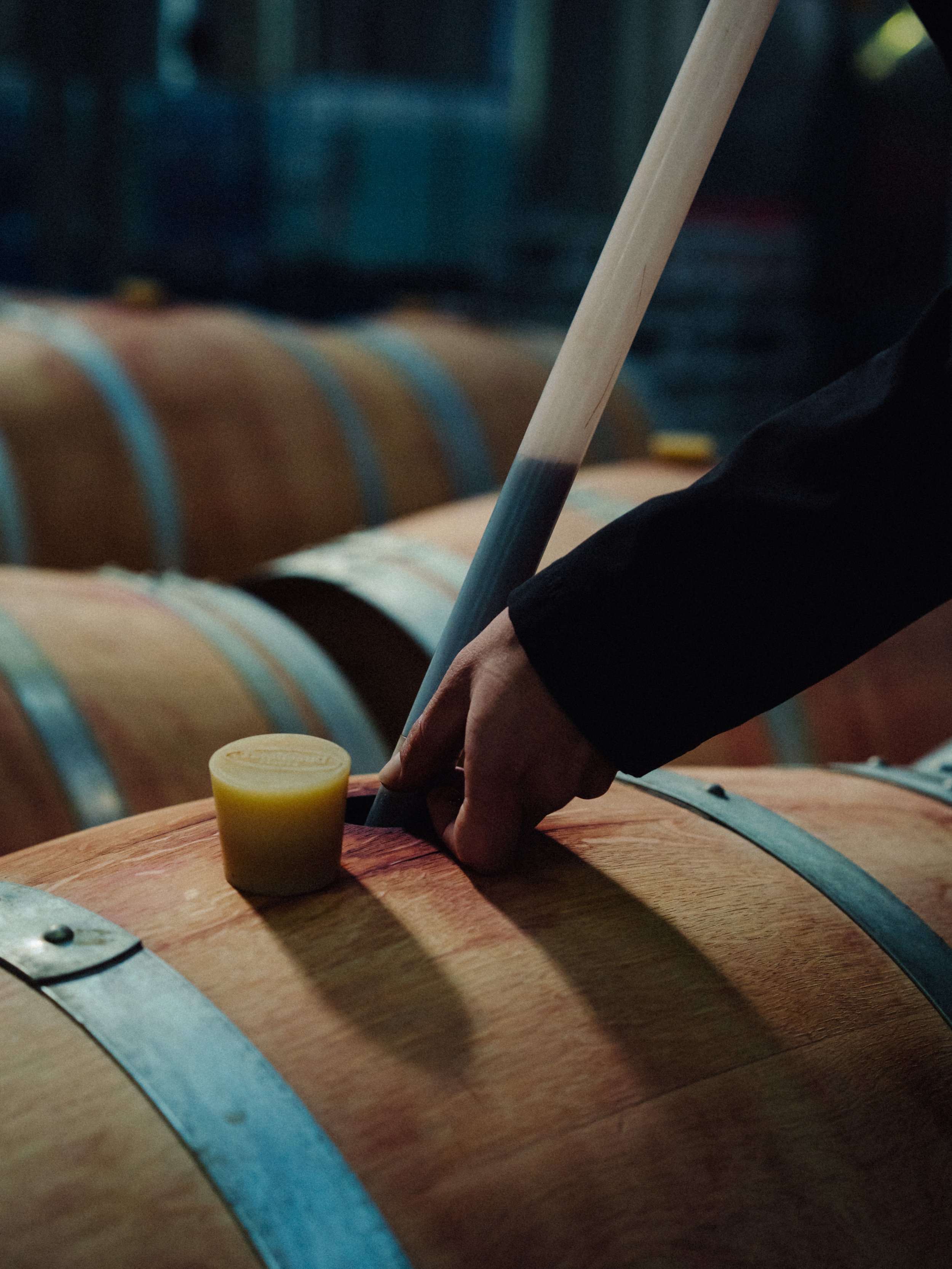 Une personne en train de boucher un fût de vin en utilisant un maillet en bois.
