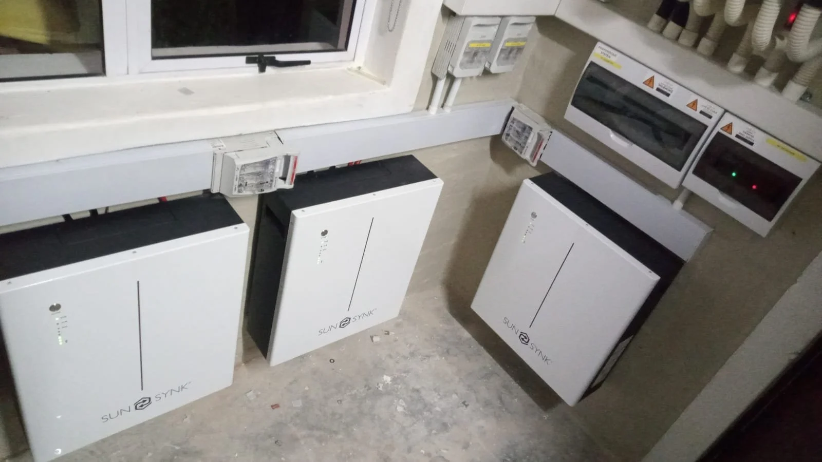 Electrical equipment including solar inverter units, circuit breakers, and switches installed near a window.