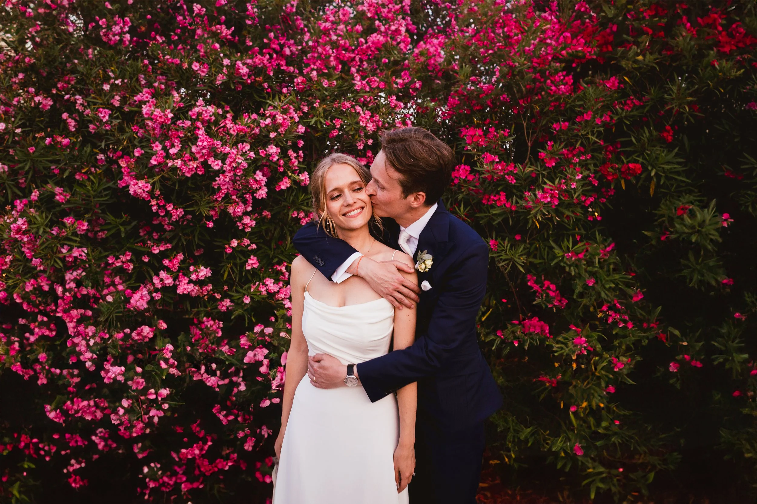 photo graphique et colorée d'un couple s'embrassant devant un laurier rose en provence, lors de leur mariage