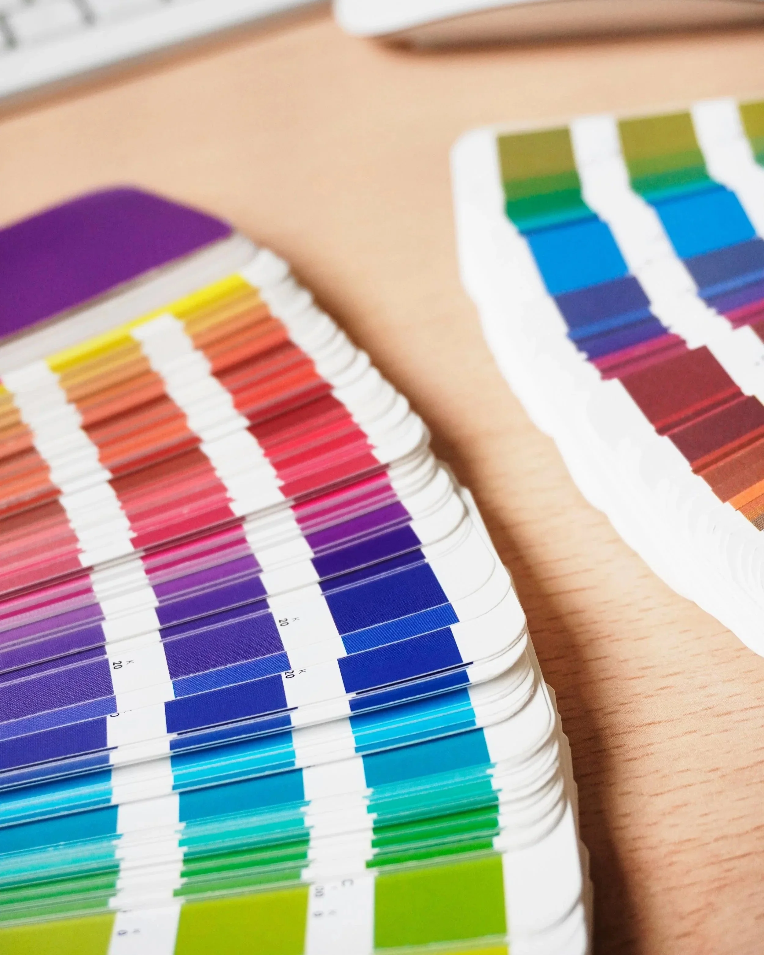 Échantillons de nuanciers de couleurs disposés sur une table en bois.
