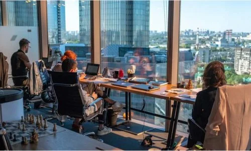People working in an office conference room with large windows and city views.