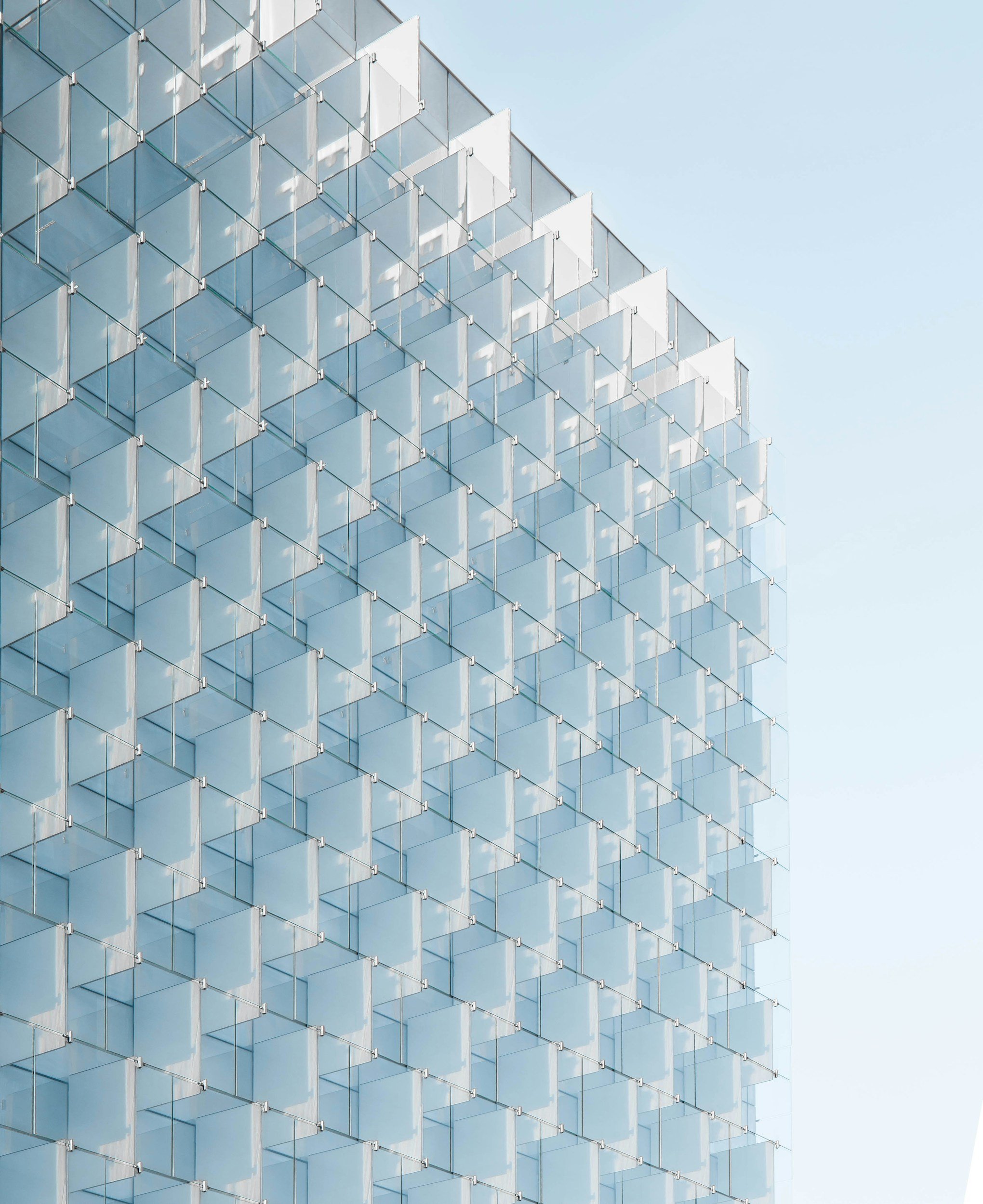 Close-up of a modern glass building reflecting the sky and clouds.