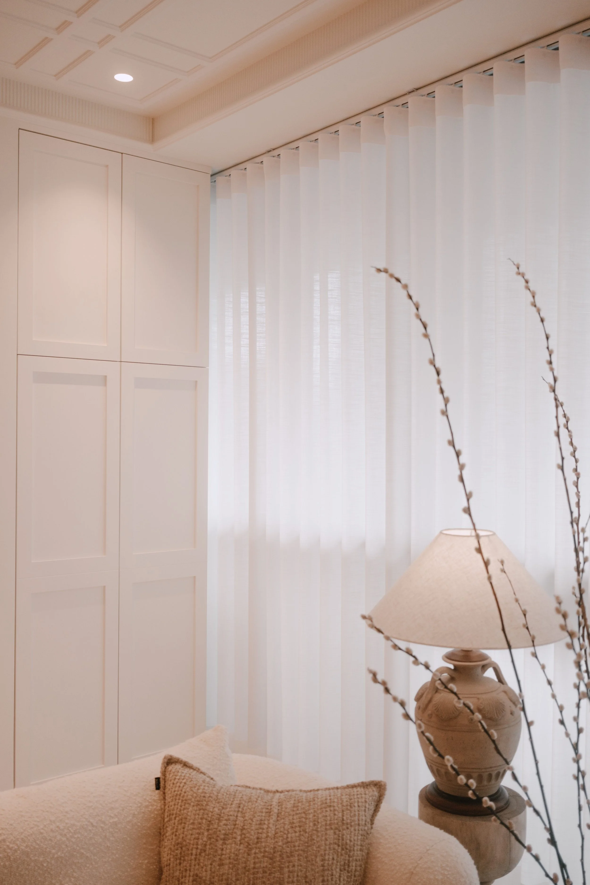 Lucent™ curtains softly filtering daylight in a cream-toned living space with warm lighting and decorative branches.