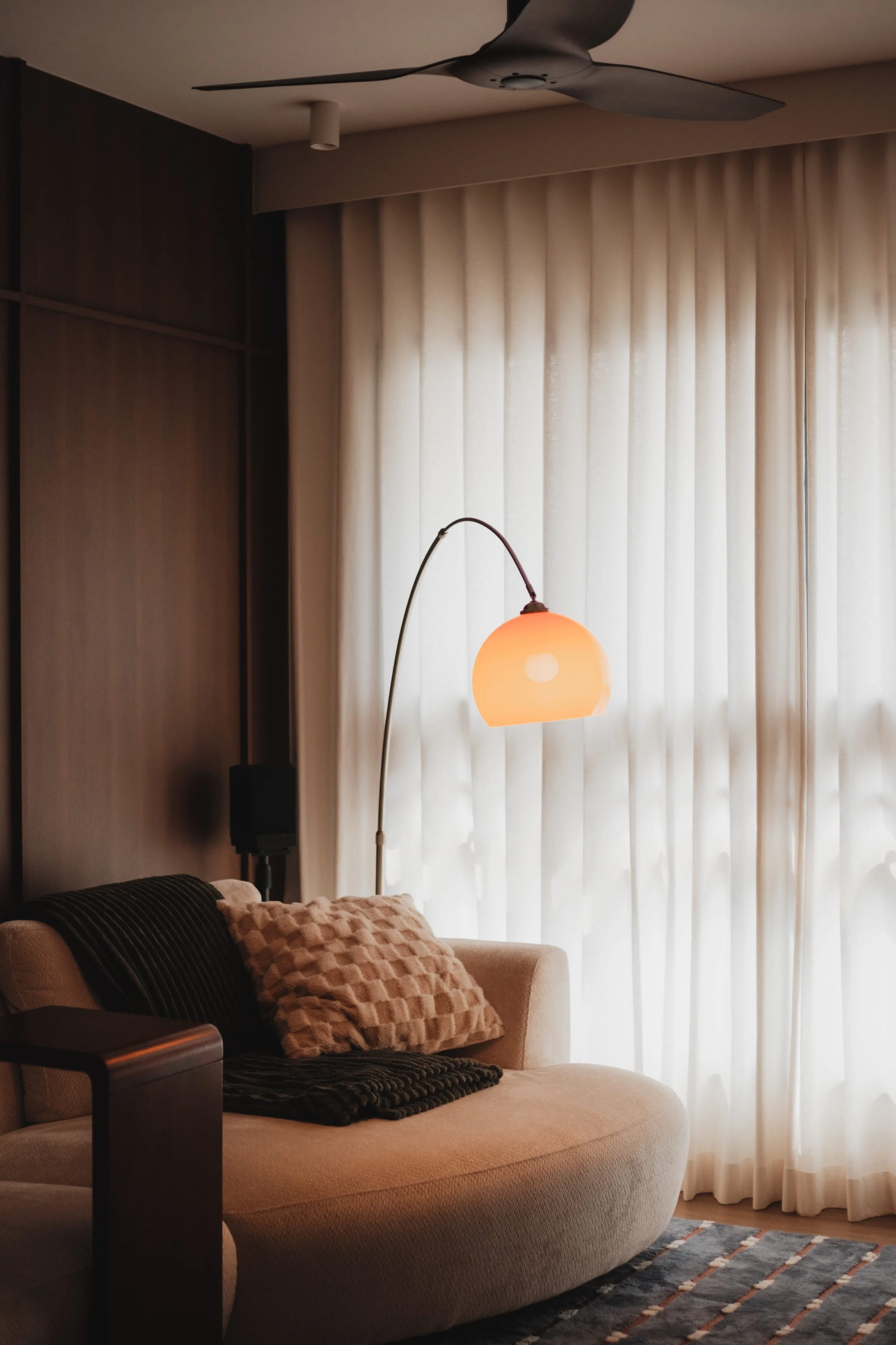 Lucent™ curtains filtering soft natural light in a warm Singapore living room with cosy furniture and ambient lighting.