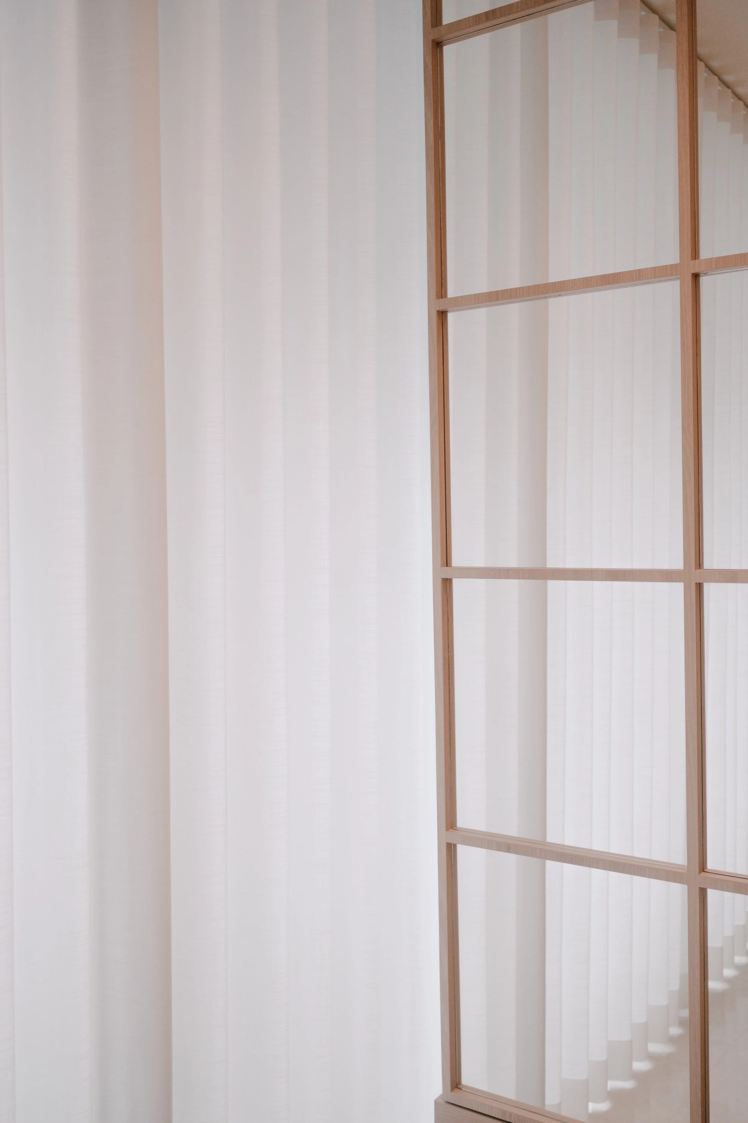 Close-up of Lucent™ curtains beside a mirror with decorative wood framing, adding softness to a warm neutral interior.