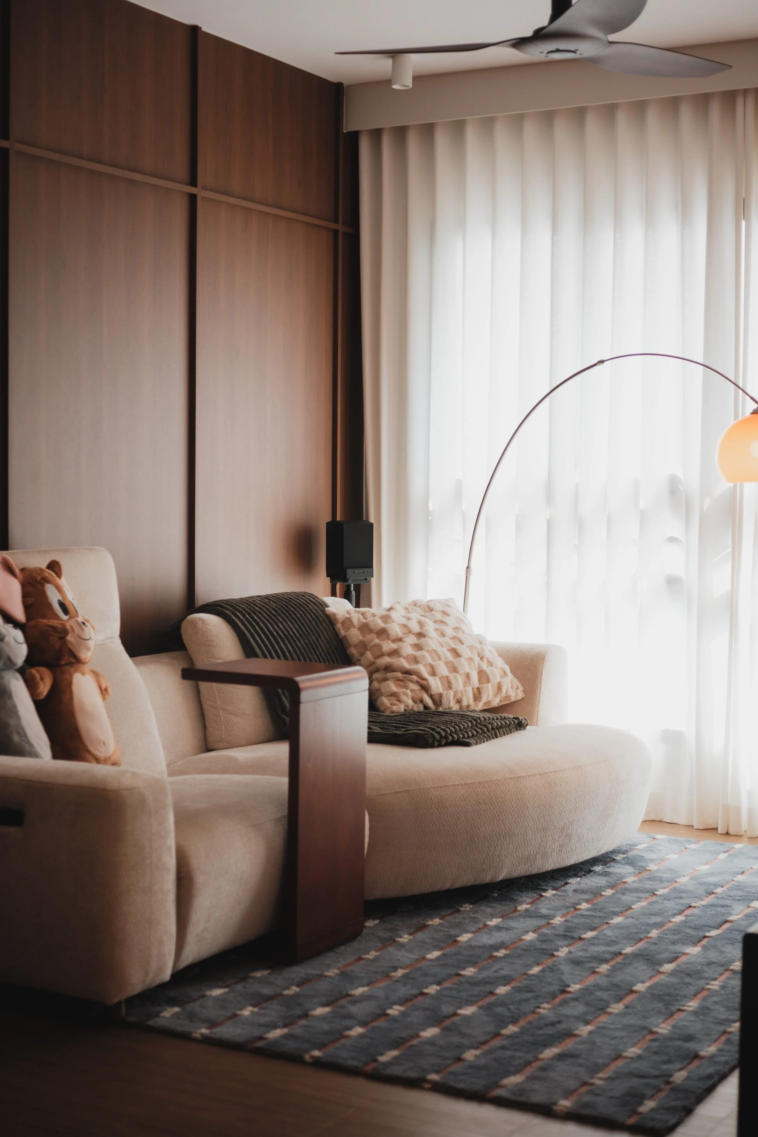 Lucent™ curtains filtering soft natural light in a warm Singapore living room with a wood and colorful interior.
