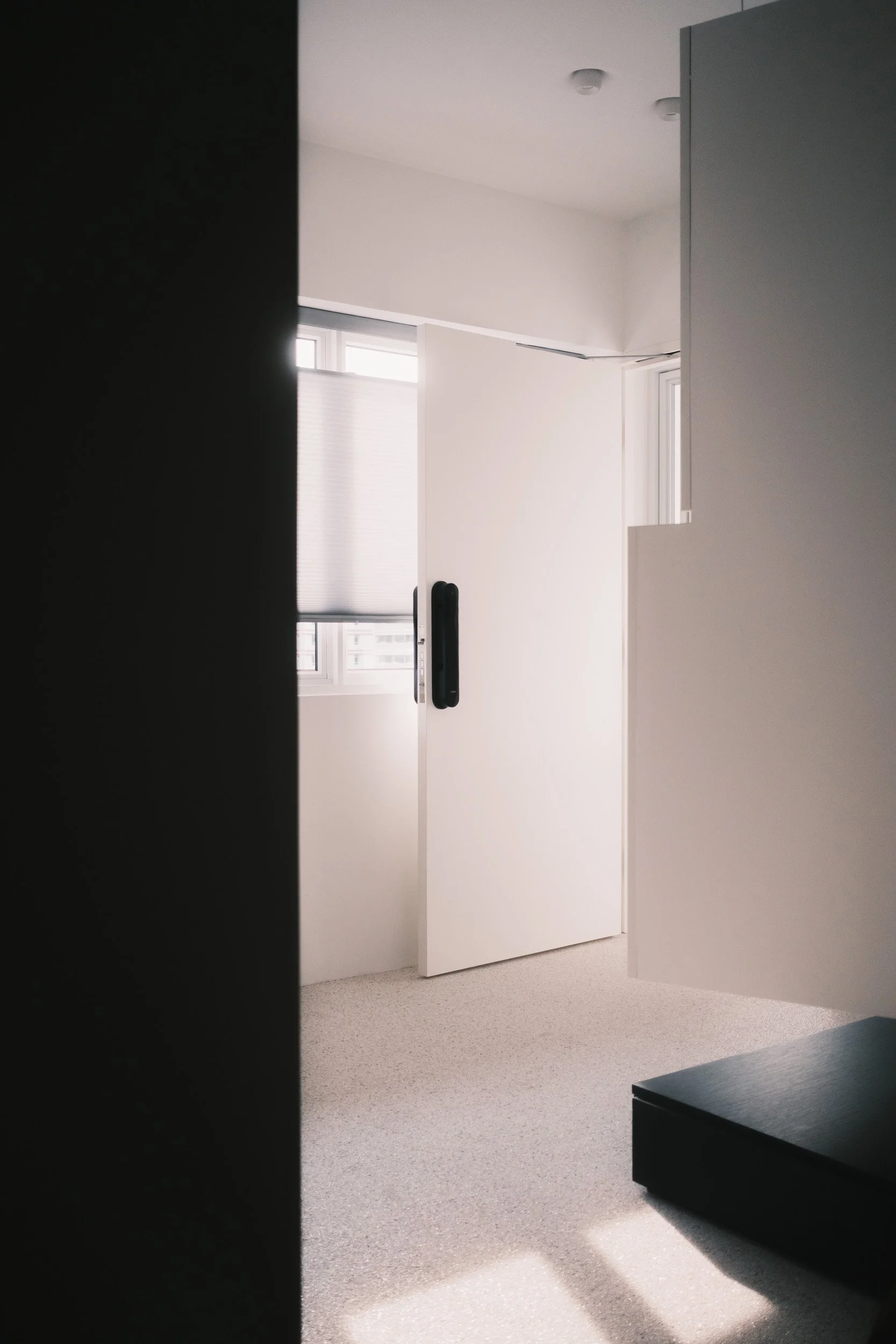 Honeycomb Blinds filtering sunlight softly, casting soft shadows across the textured floor in the entrance of a HDB home in Singapore.