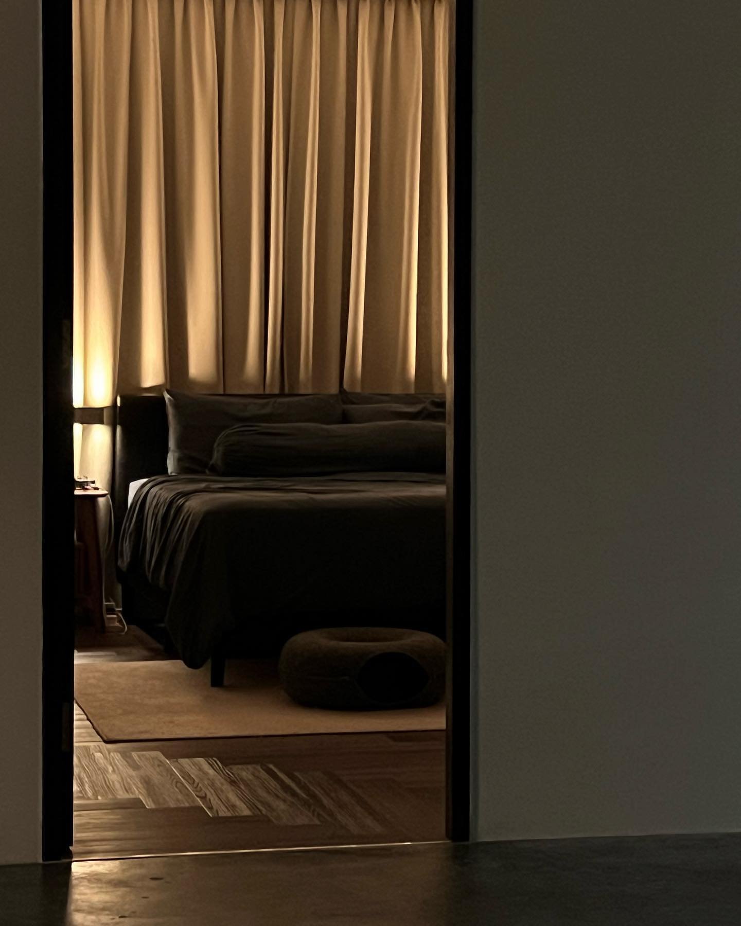 Pleated Somn™ curtains creating a restful bedroom setting with warm ambient light and a dark, moody interior.