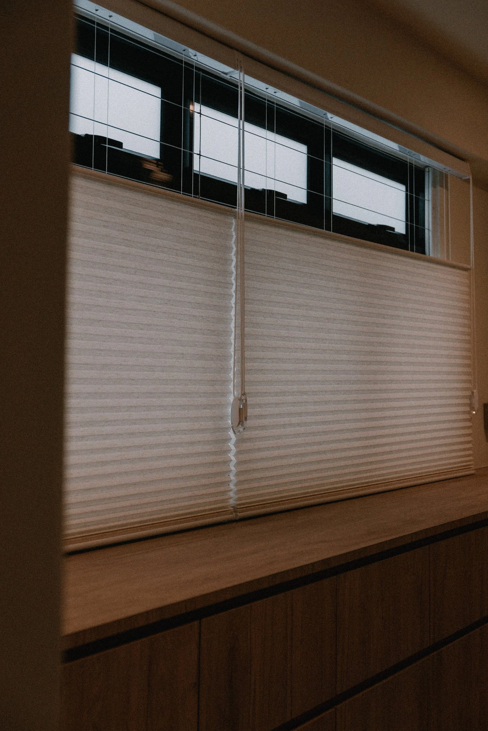 Honeycomb blinds covering a wide window in a warm Singapore dining area, providing privacy and soft natural light control.