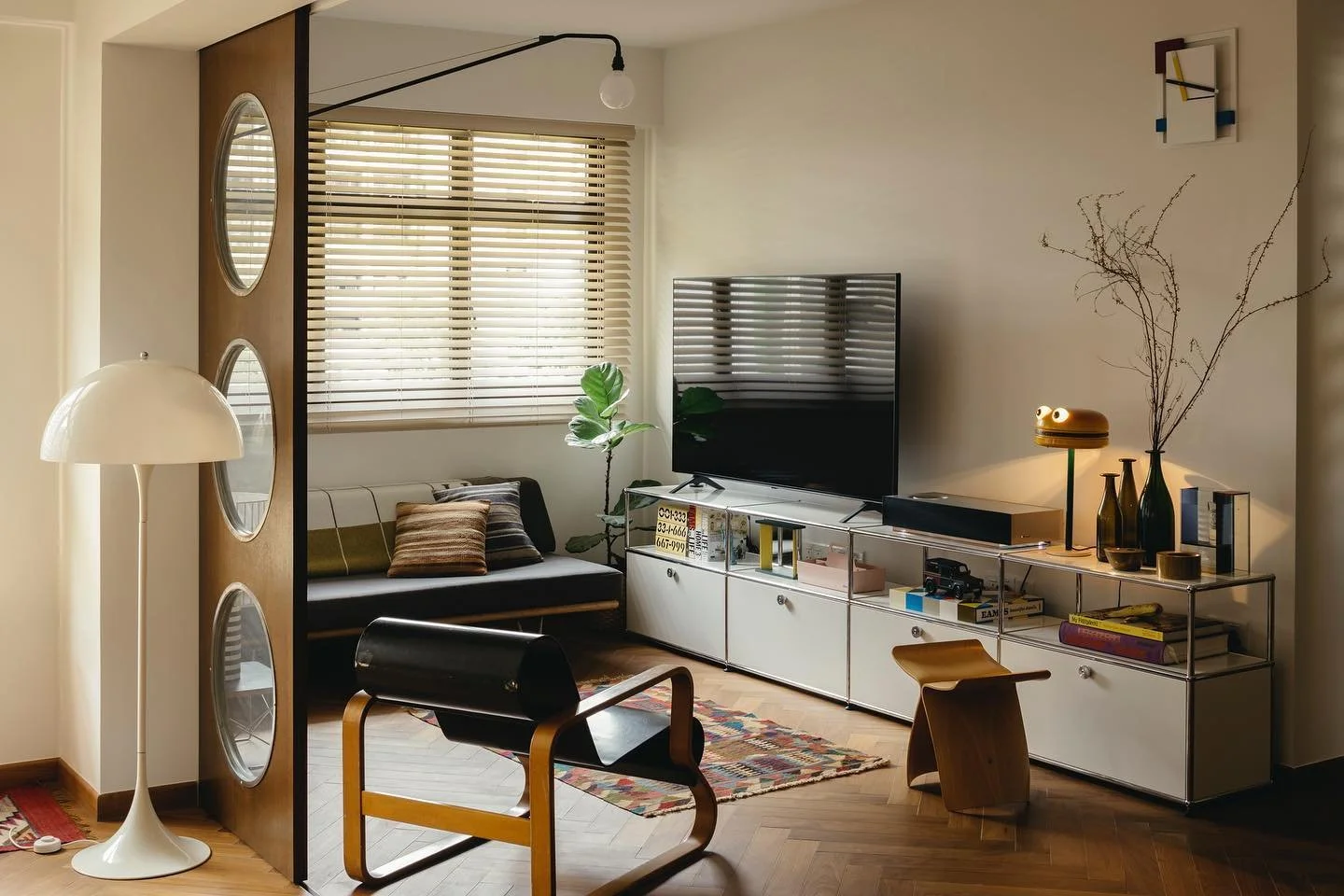 Venetian blinds filtering natural light in an eclectic Singapore living room with vintage furniture, warm wood tones and decorative wall mirrors.