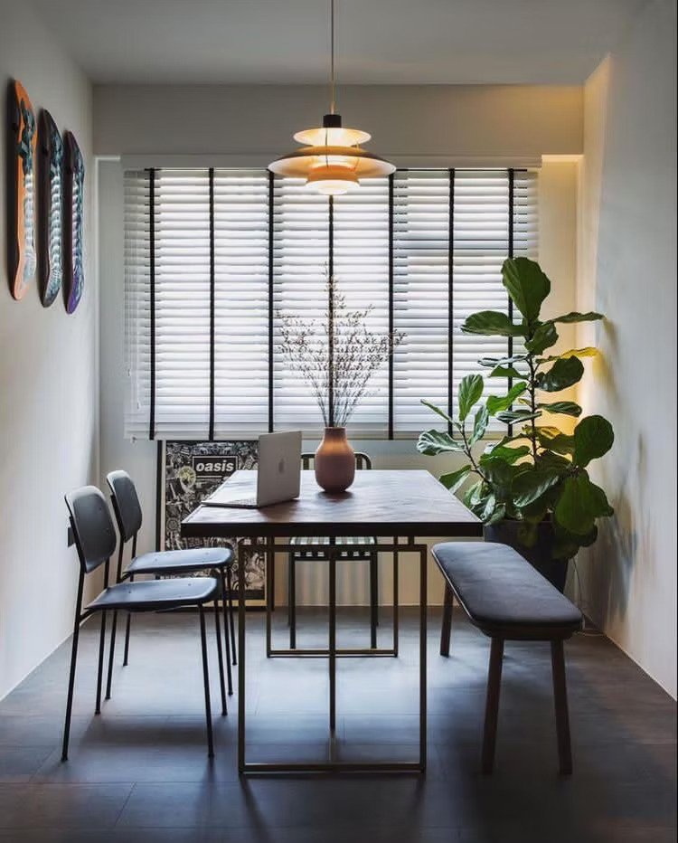 Everyday Curtains Singapore Venetian blinds in a dining area with horizontal white slats, black ladder tapes, wooden table, chairs, plants, and warm lighting.