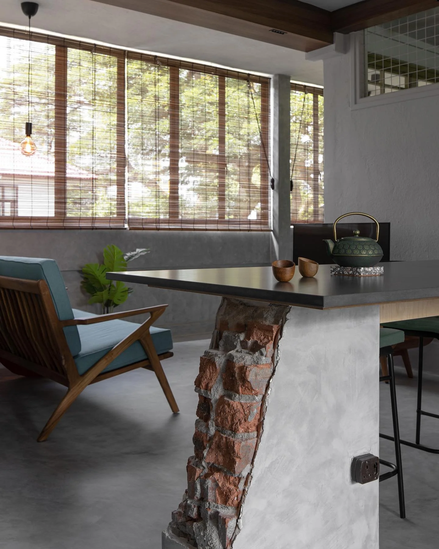 Woven wood outdoor blinds filtering natural light in a cosy balcony dining area with greenery and natural textures.