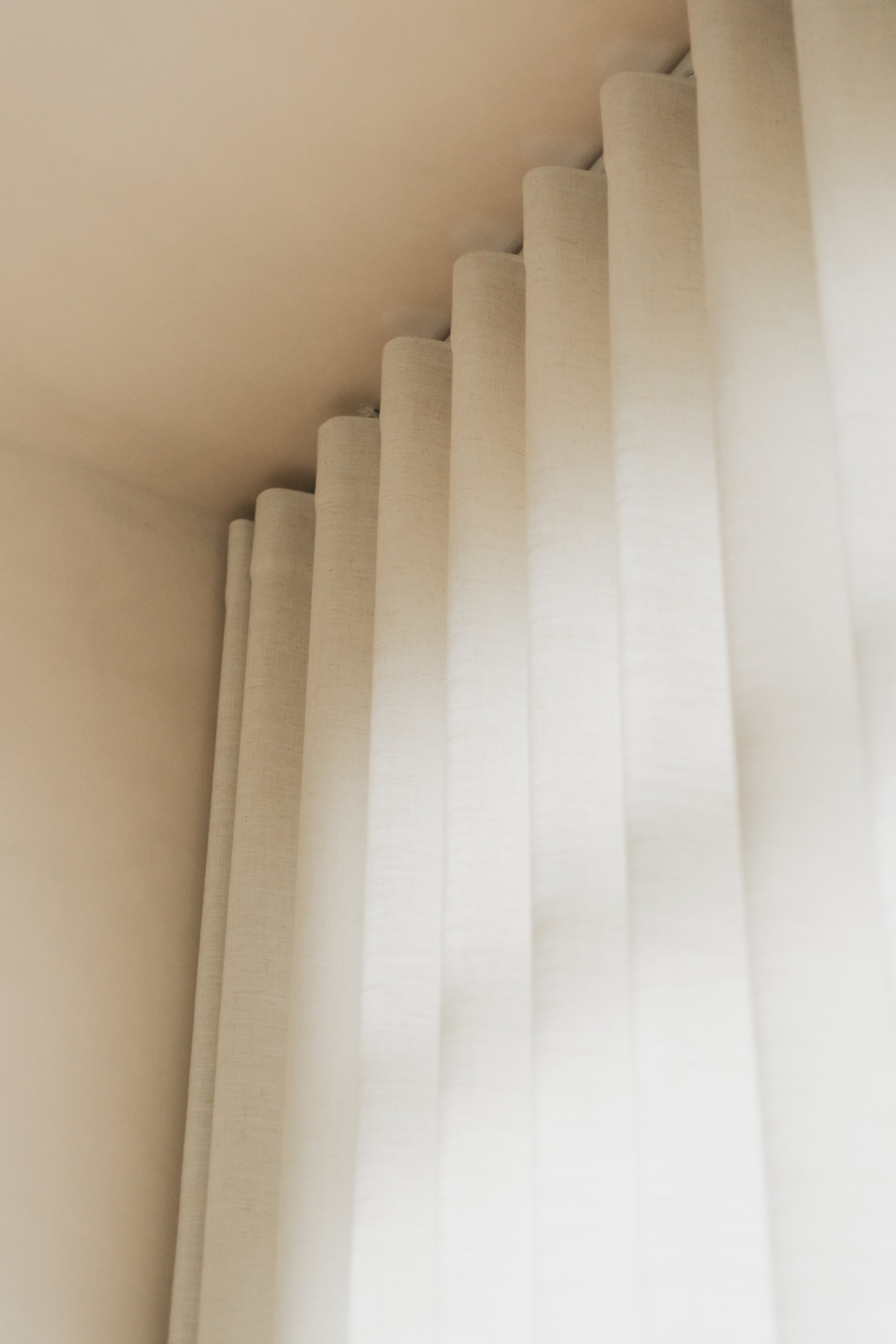 Close-up of Lucent™ curtains with soft fabric folds, gently filtering natural light into a warm neutral home in Singapore.