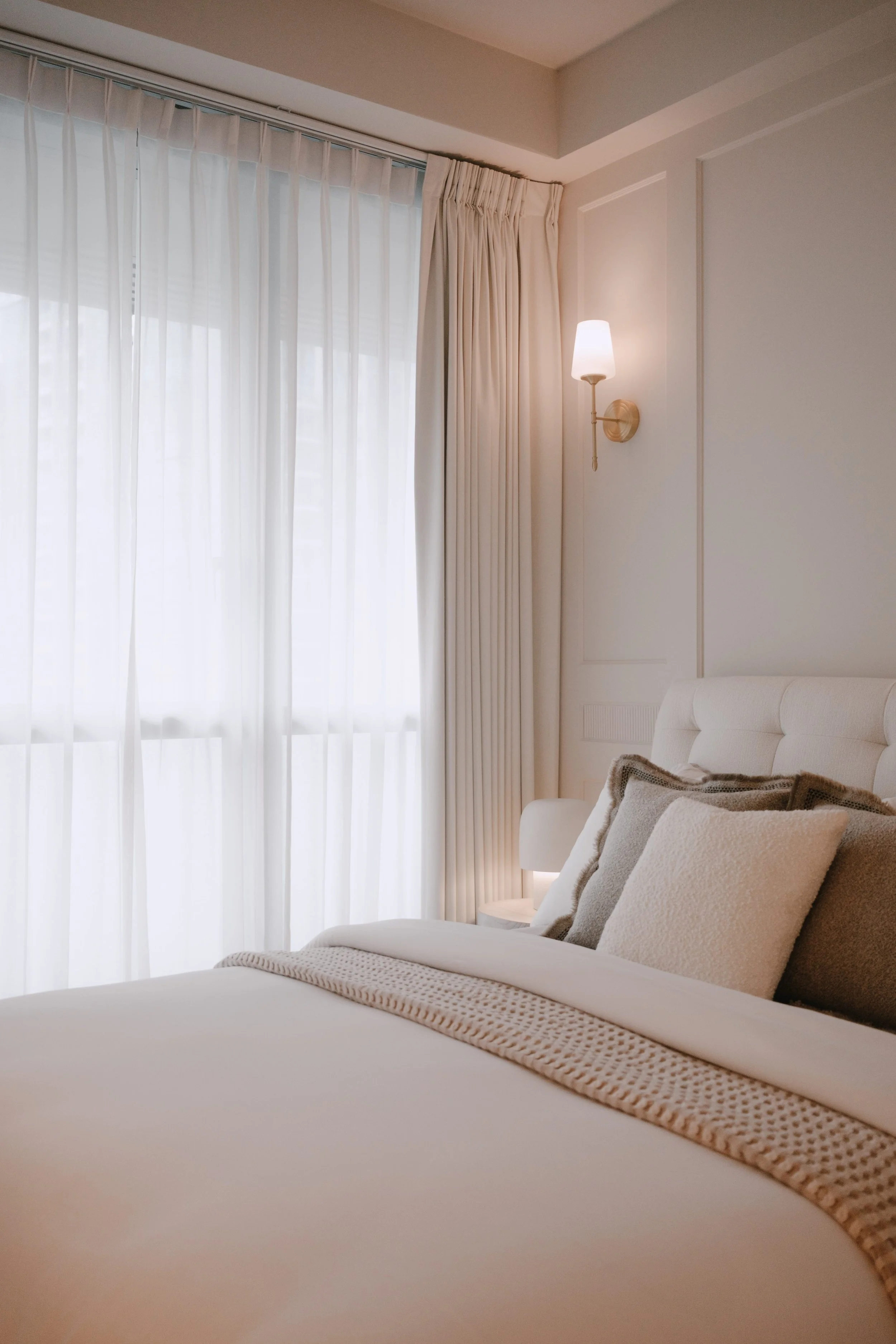 Lucent™  and Somn™ curtains in a serene bedroom, softly filtering natural light beside warm neutral bedding.