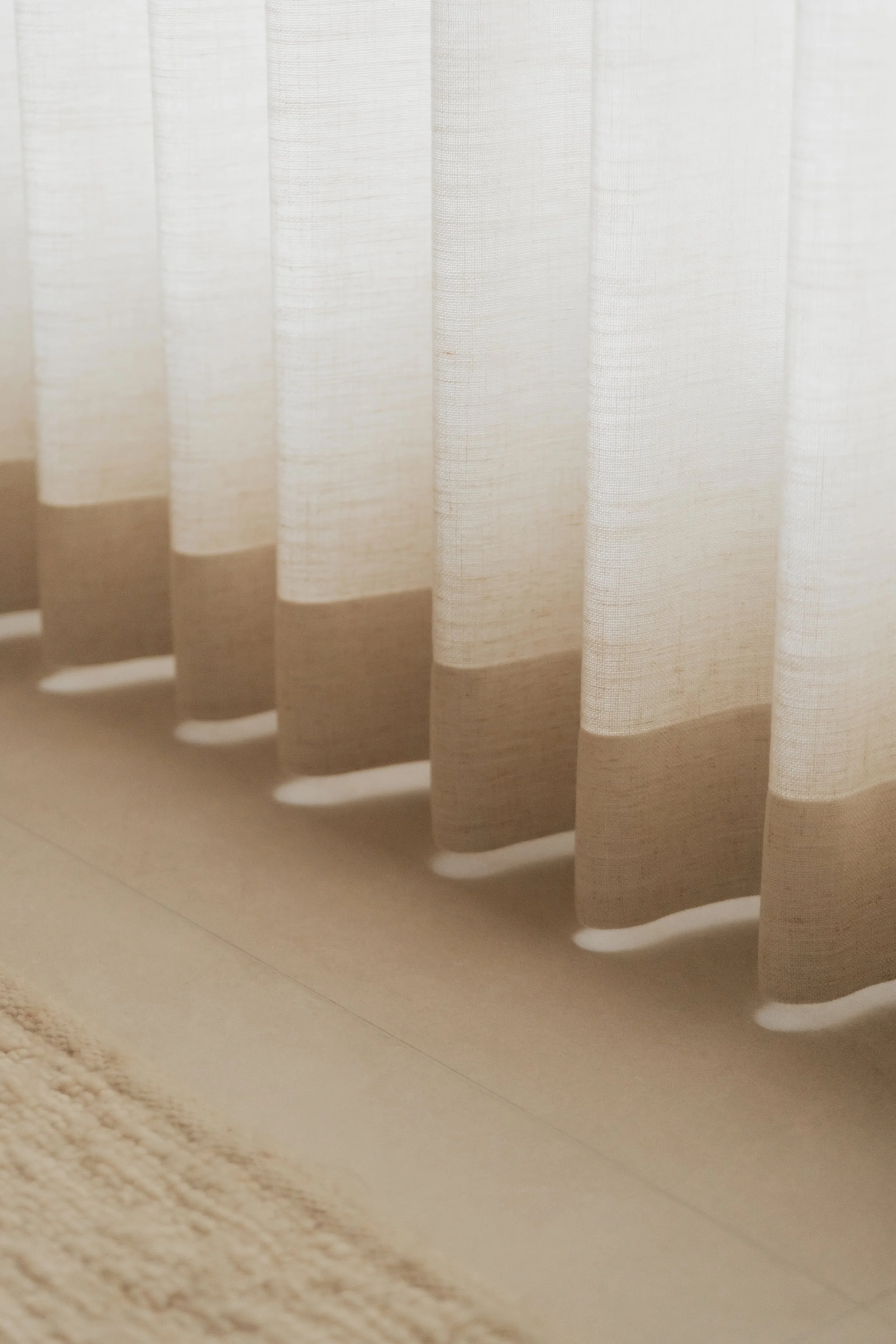 Close-up of Lucent™ curtains with soft fabric folds, gently filtering natural light into a warm neutral home.
