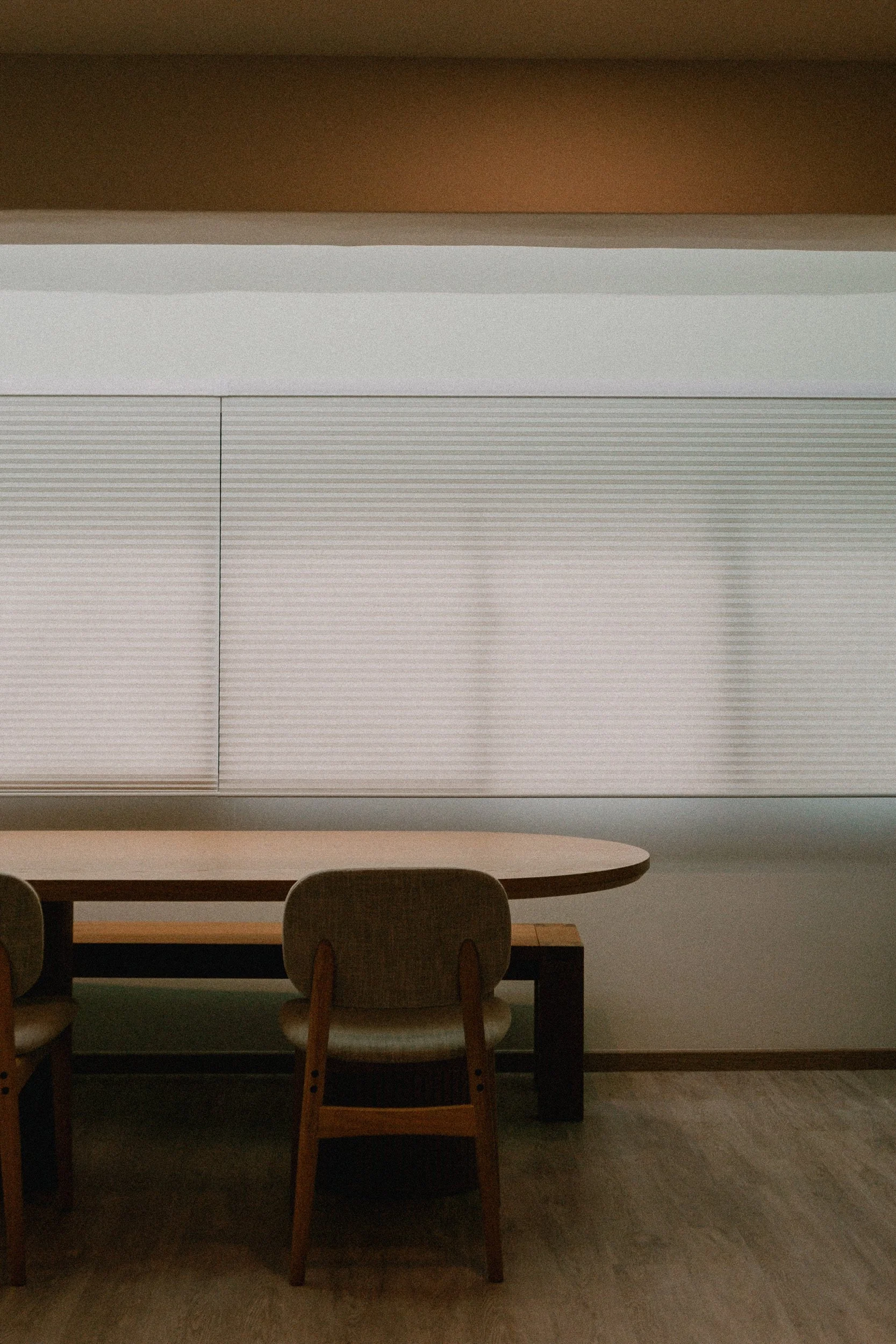 Honeycomb blinds in a Singapore dining area, creating a clean backdrop behind a wooden dining table and chairs.