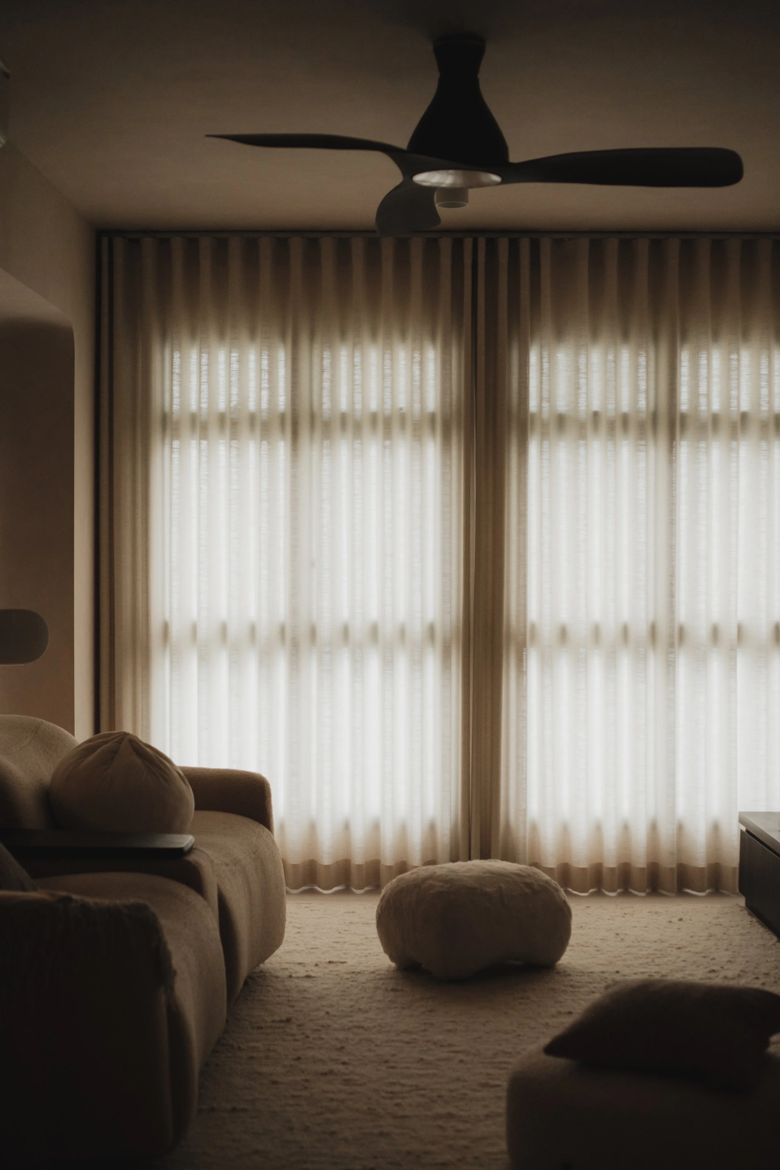 Full-height Lucent™ curtains softly filtering natural light in a warm, cosy Singapore living room.