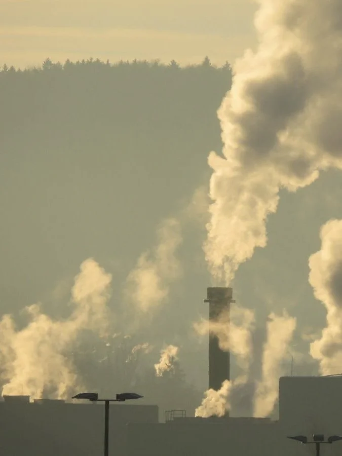 Hazy city skyline with heavy air pollution, showing dense smog hanging over buildings and reducing visibility.