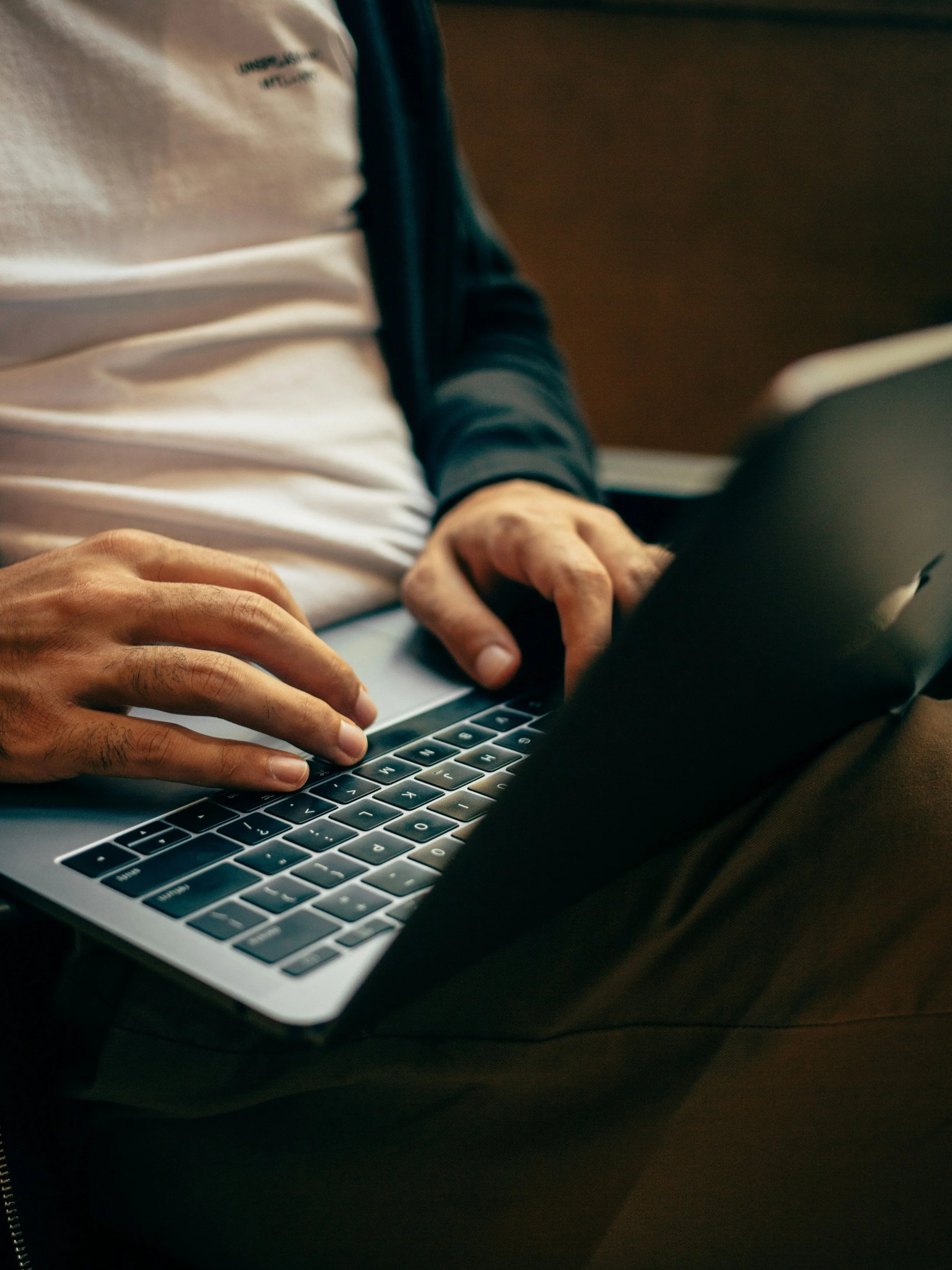 Close-up of a man sitting and using a laptop to complete an online form.