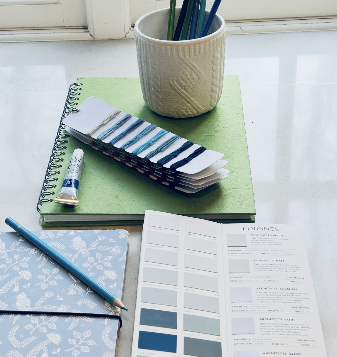 Interior design color consultation materials featuring blue paint swatches, fabric threads, and notebooks by the new room in Sevenoaks.