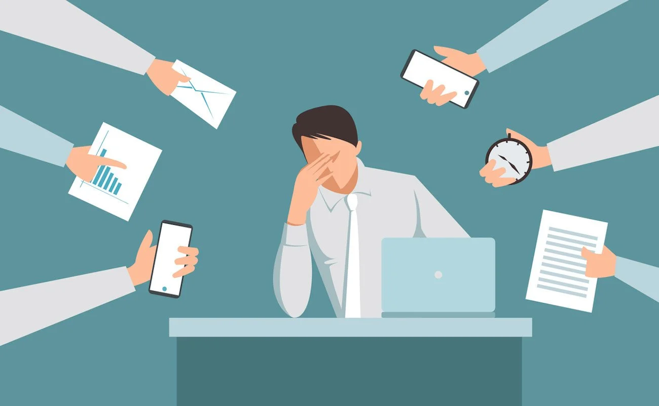 A person sitting at a desk with a laptop, surrounded by multiple hands holding papers, charts, a phone, a stopwatch, an envelope, and a document, all hovering around him, indicating stress or overwhelm.
