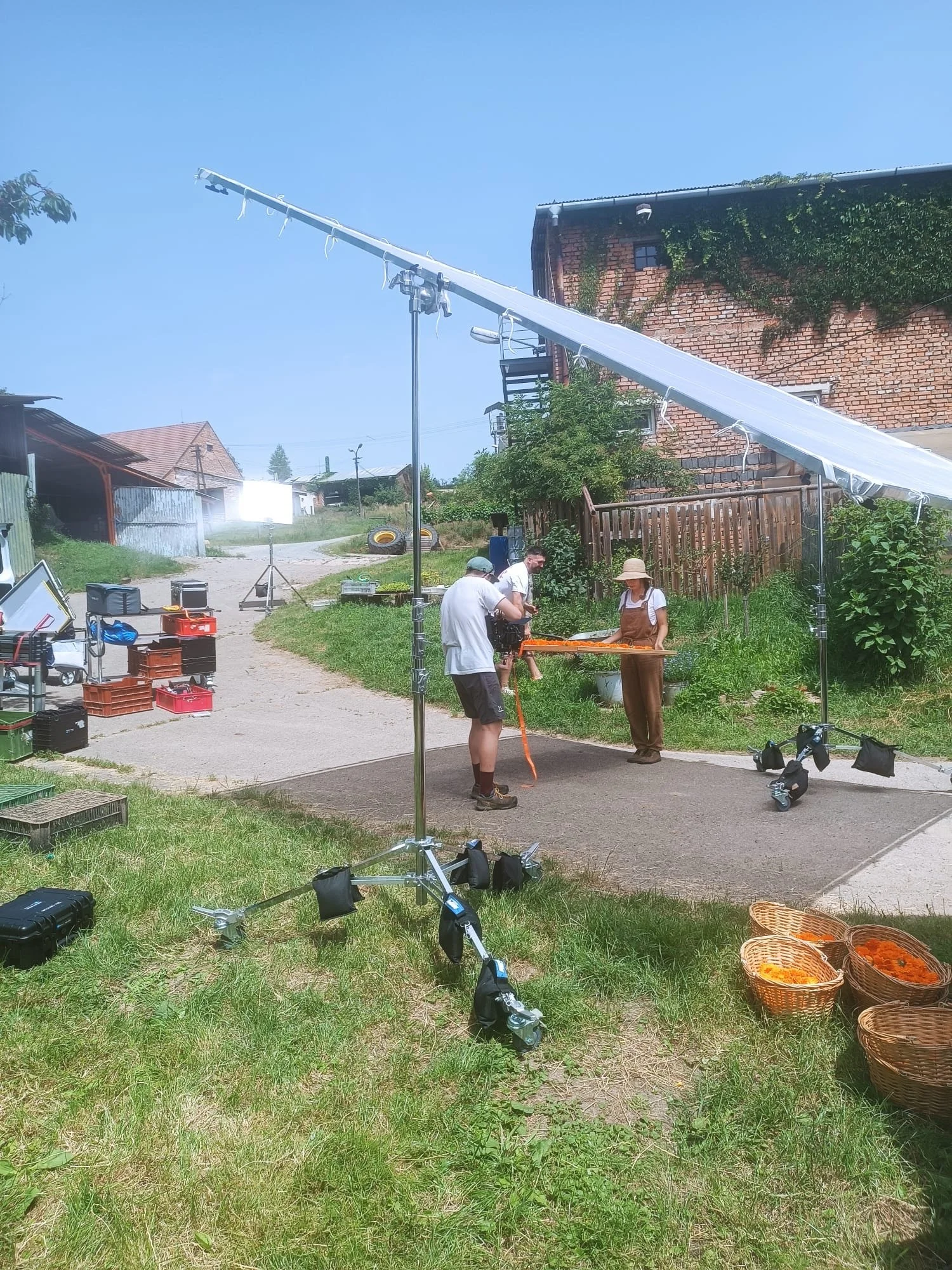 A group of people working on a film shoot outdoors on a sunny day, with equipment set up around them.