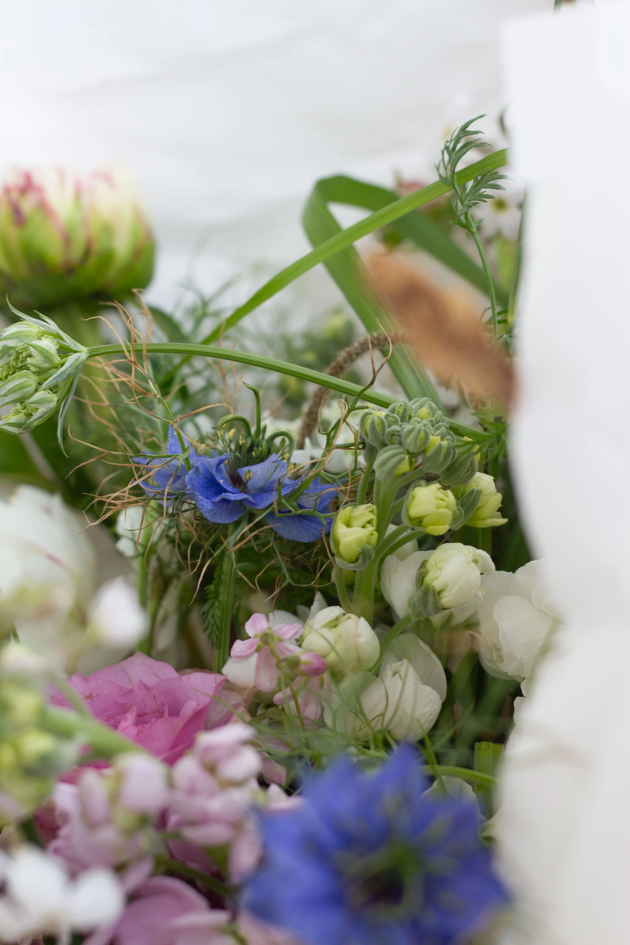 Close-up of a colorful flower bouquet with various flowers including pink, white, and blue blooms, and greenery.