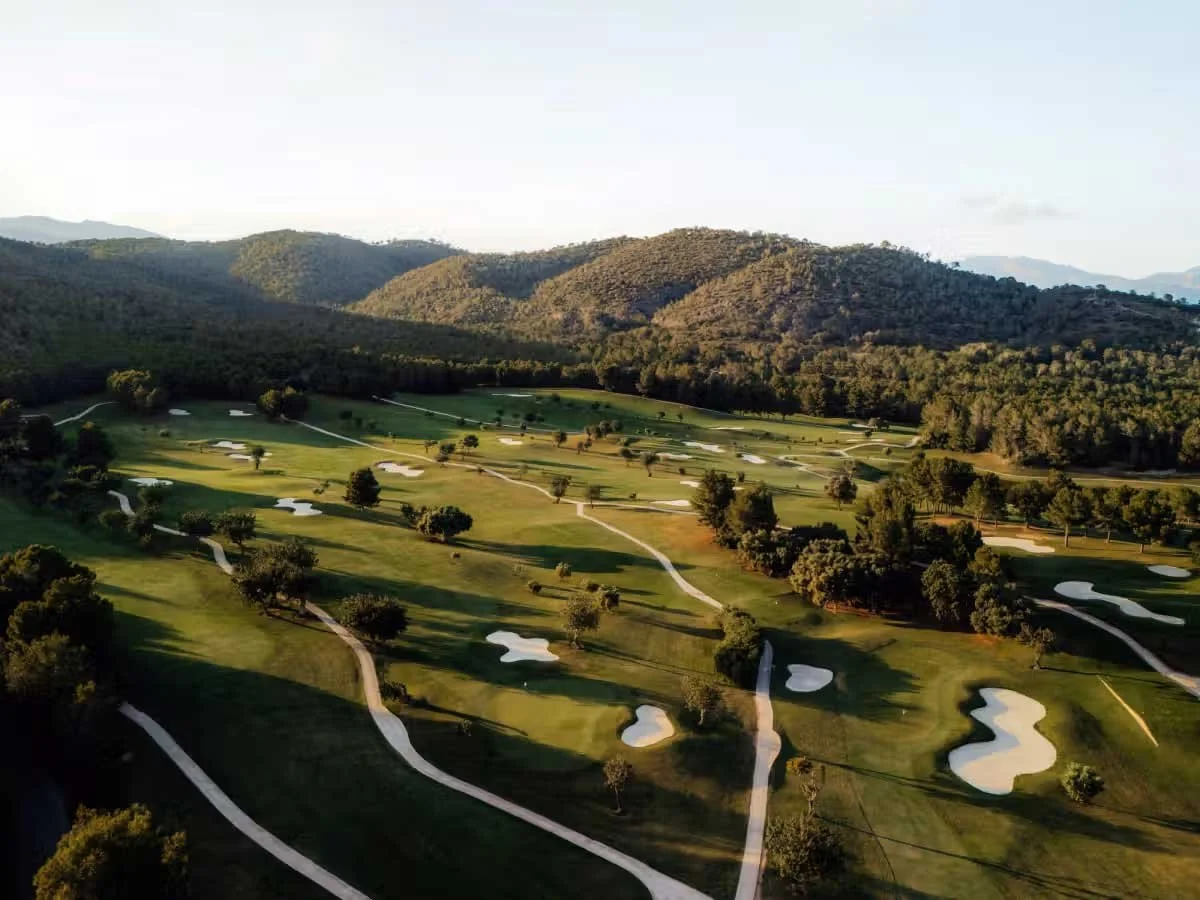 Aerial view of the Arabella Golf Mallorca courses at dusk, with the hills above Palma beyond